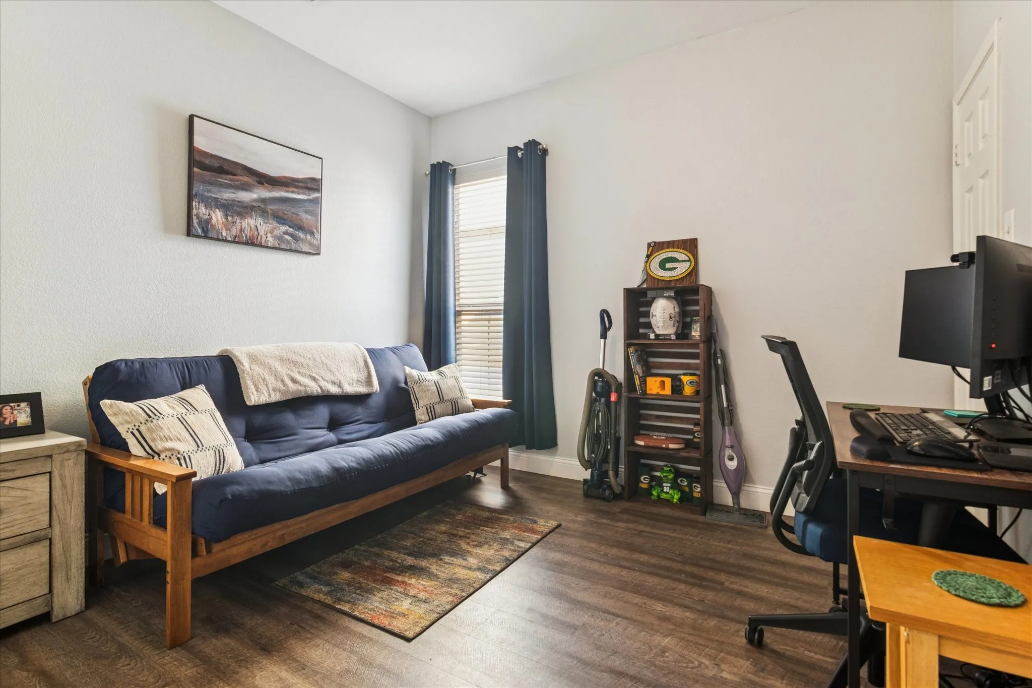 Wood-finish flooring, white walls, and a window with blinds and dark-colored curtains