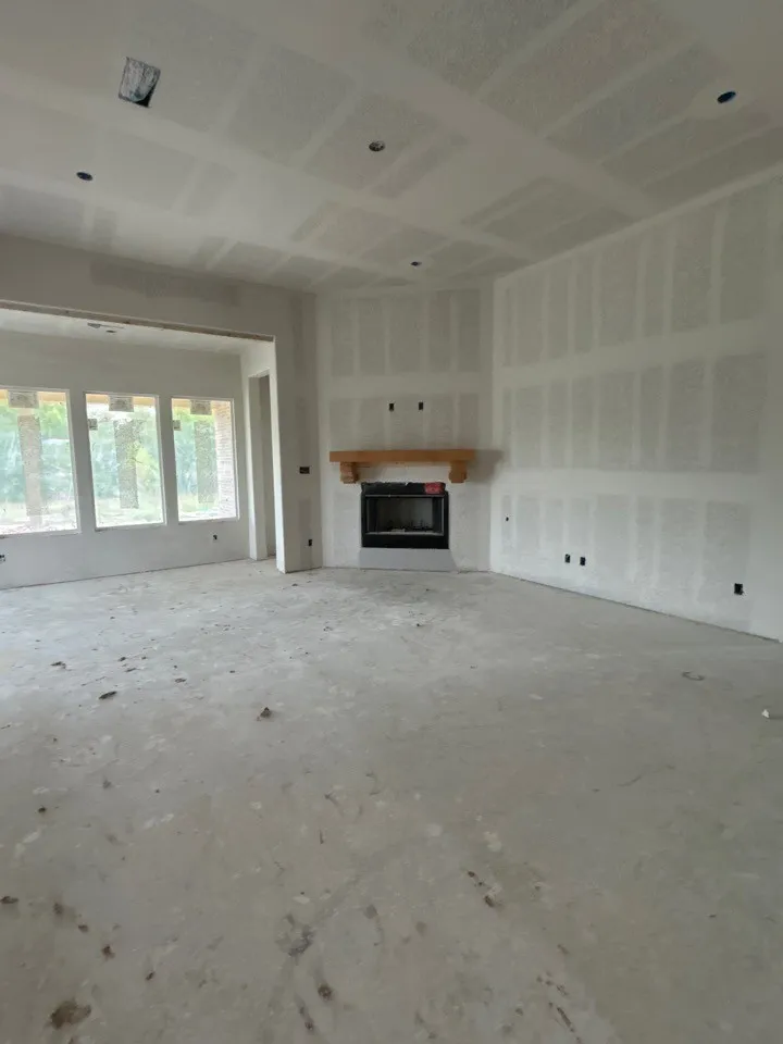 Expansive interior space with a built-in fireplace featuring a wood mantel, recessed lighting, and multiple windows