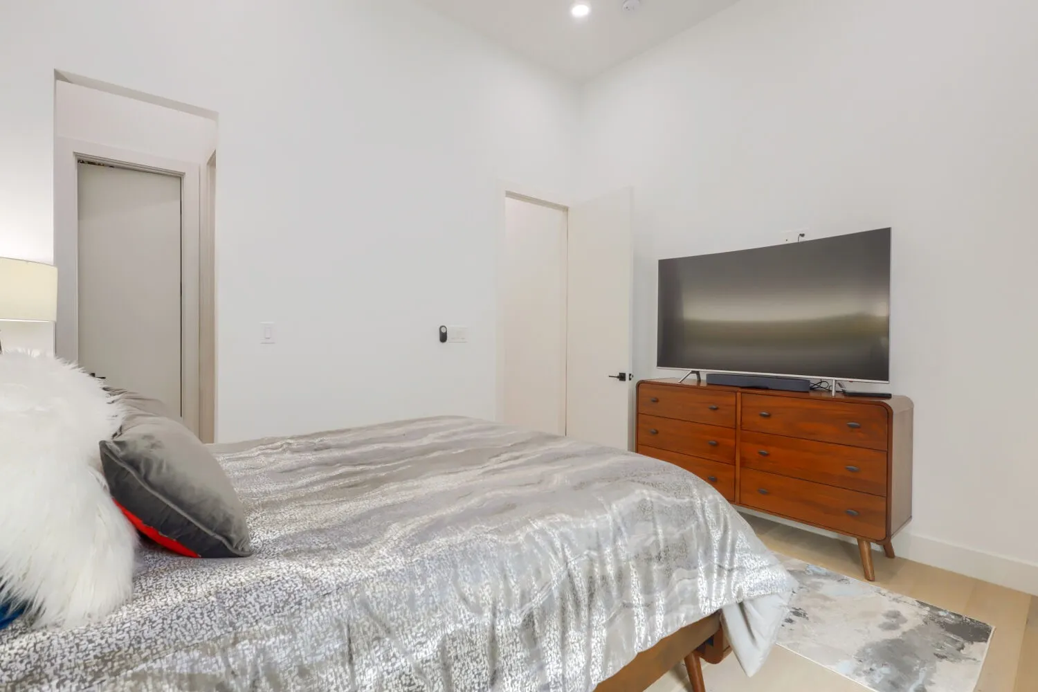 Recessed lighting, wood-finish flooring, white walls, and a modern door