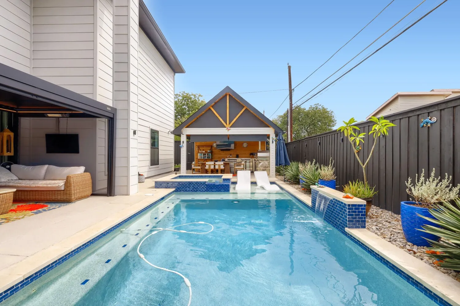 Rectangular swimming pool with integrated spa and water feature, complemented by a dedicated outdoor living structure
