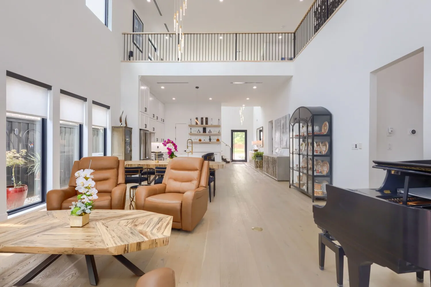 Two-story living space with a mezzanine balcony, recessed lighting, wood-finish flooring, and a contemporary chandelier