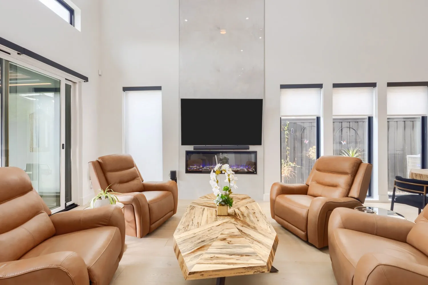 Vaulted ceilings, large format tile flooring, built-in faux fireplace, oversized sliding glass door, and clerestory window