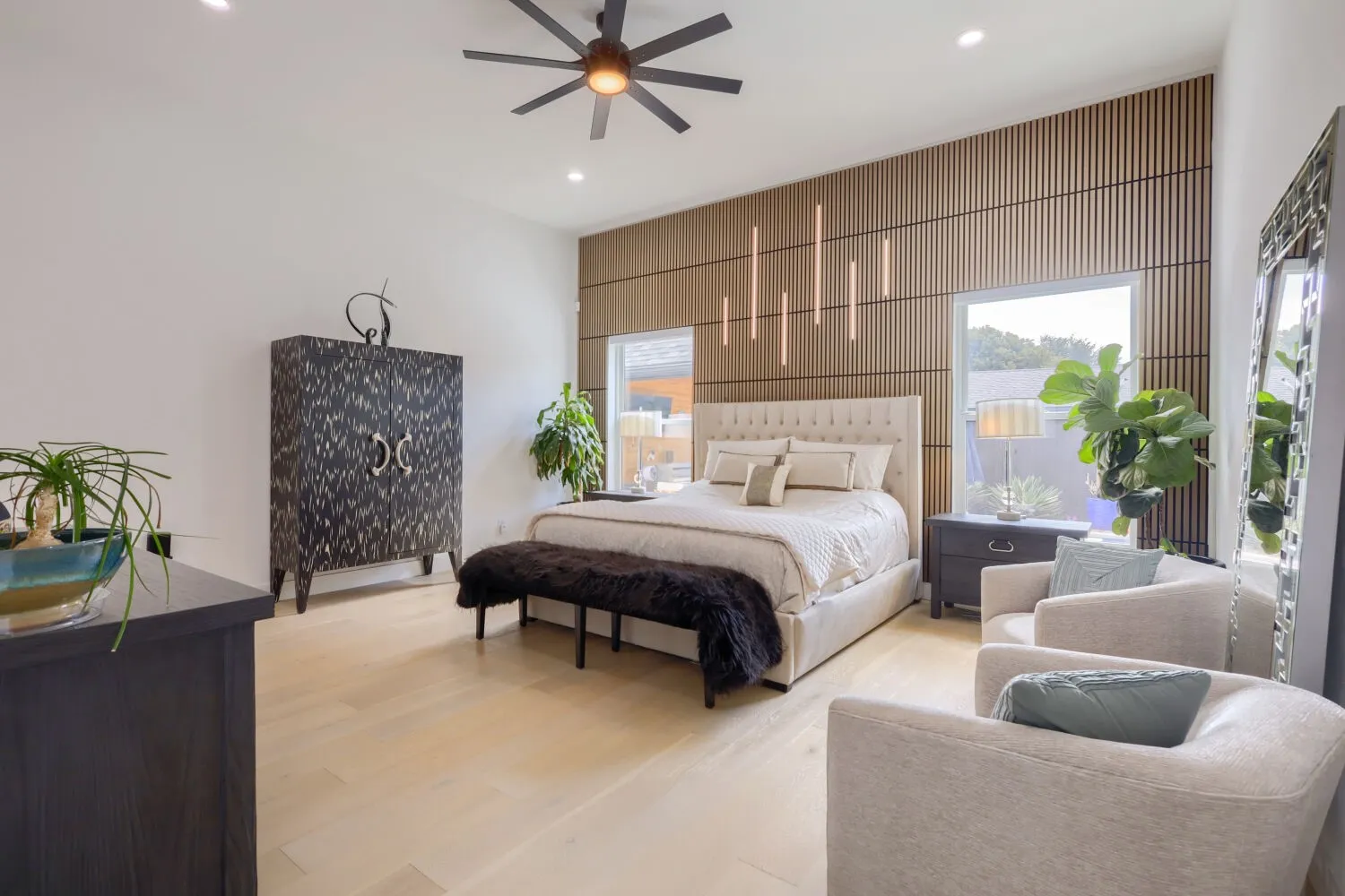 Wood-finish flooring, recessed lighting, ceiling fan, and a wood-slatted accent wall with integrated vertical lighting