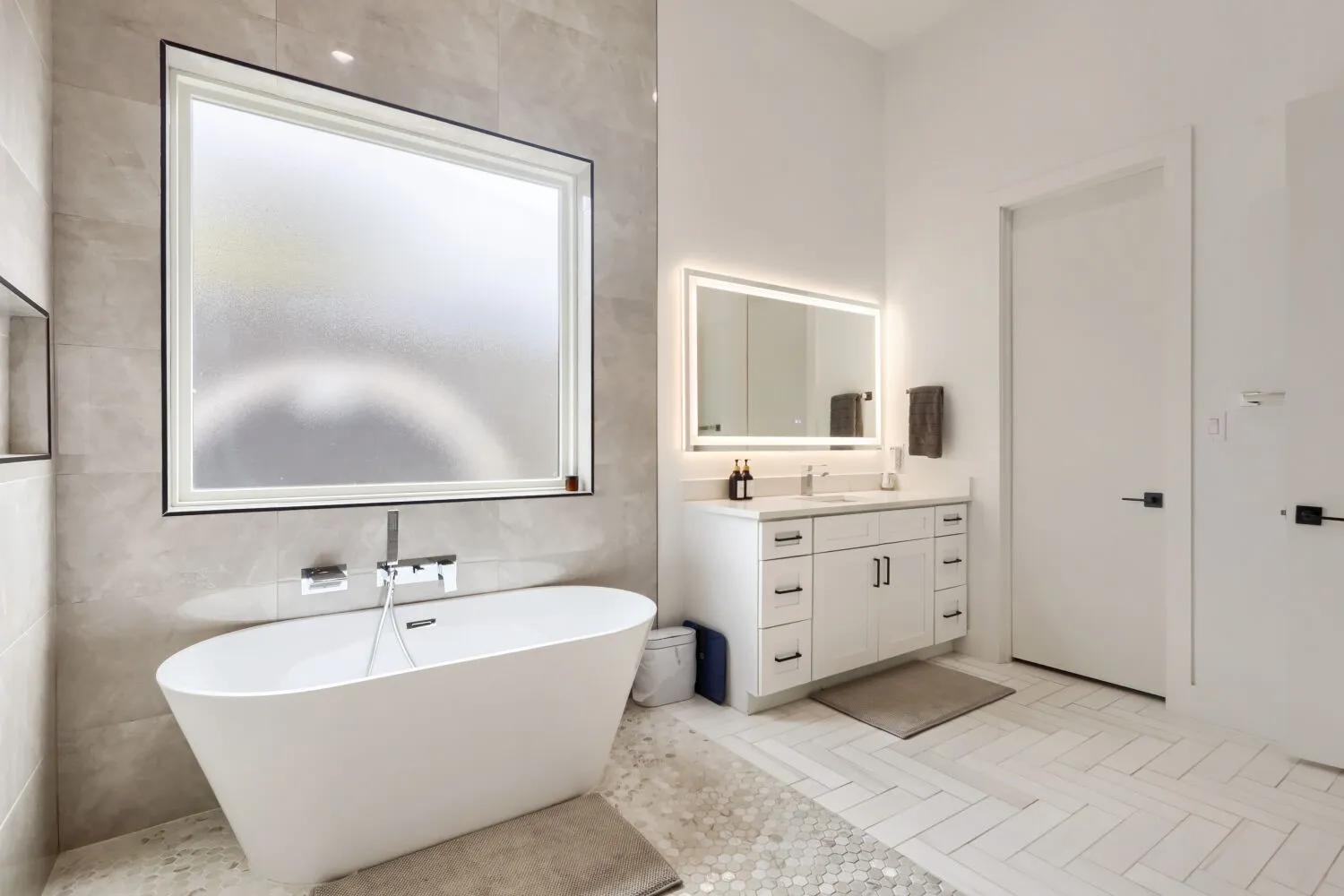 Freestanding soaking tub with a wall-mounted faucet, complemented by a large frosted window