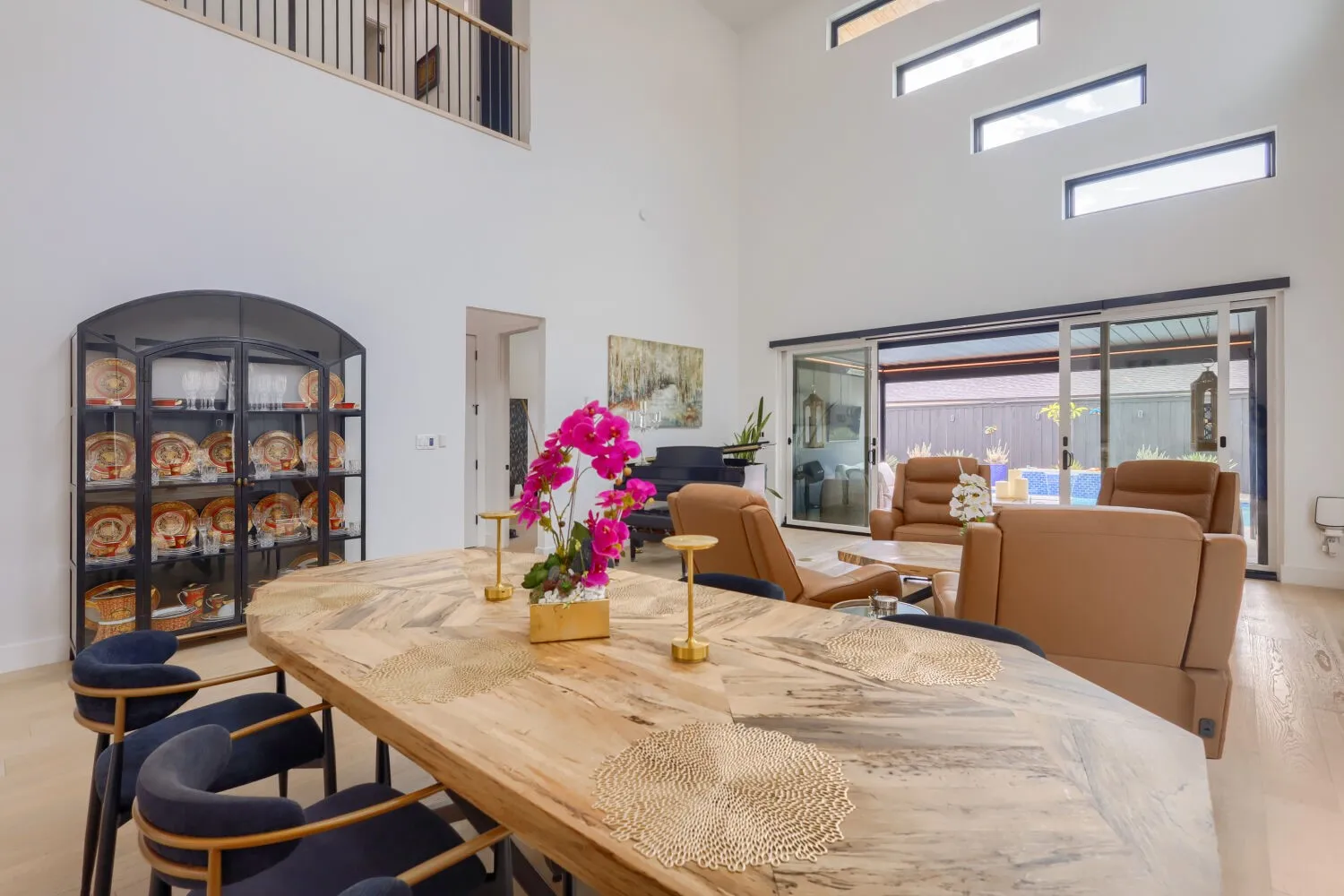 Vaulted ceilings with high-set windows, wood-finish flooring, and sliding glass doors