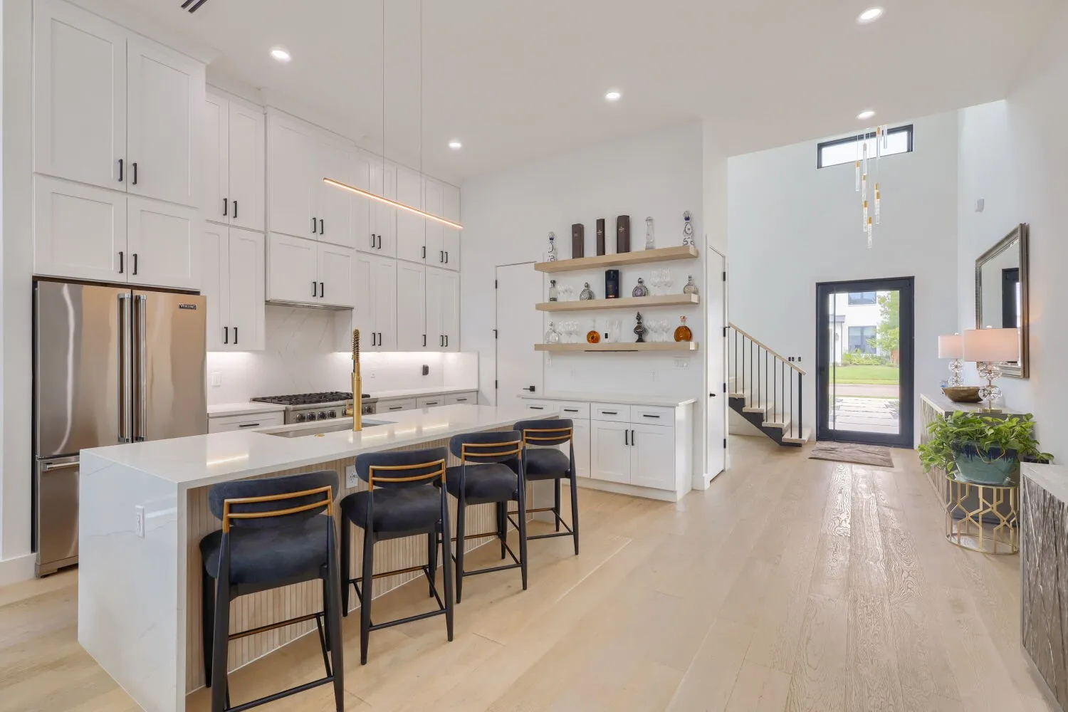 Contemporary kitchen with an expansive island featuring seating, stainless steel appliances, white cabinetry, and wood-finish flooring