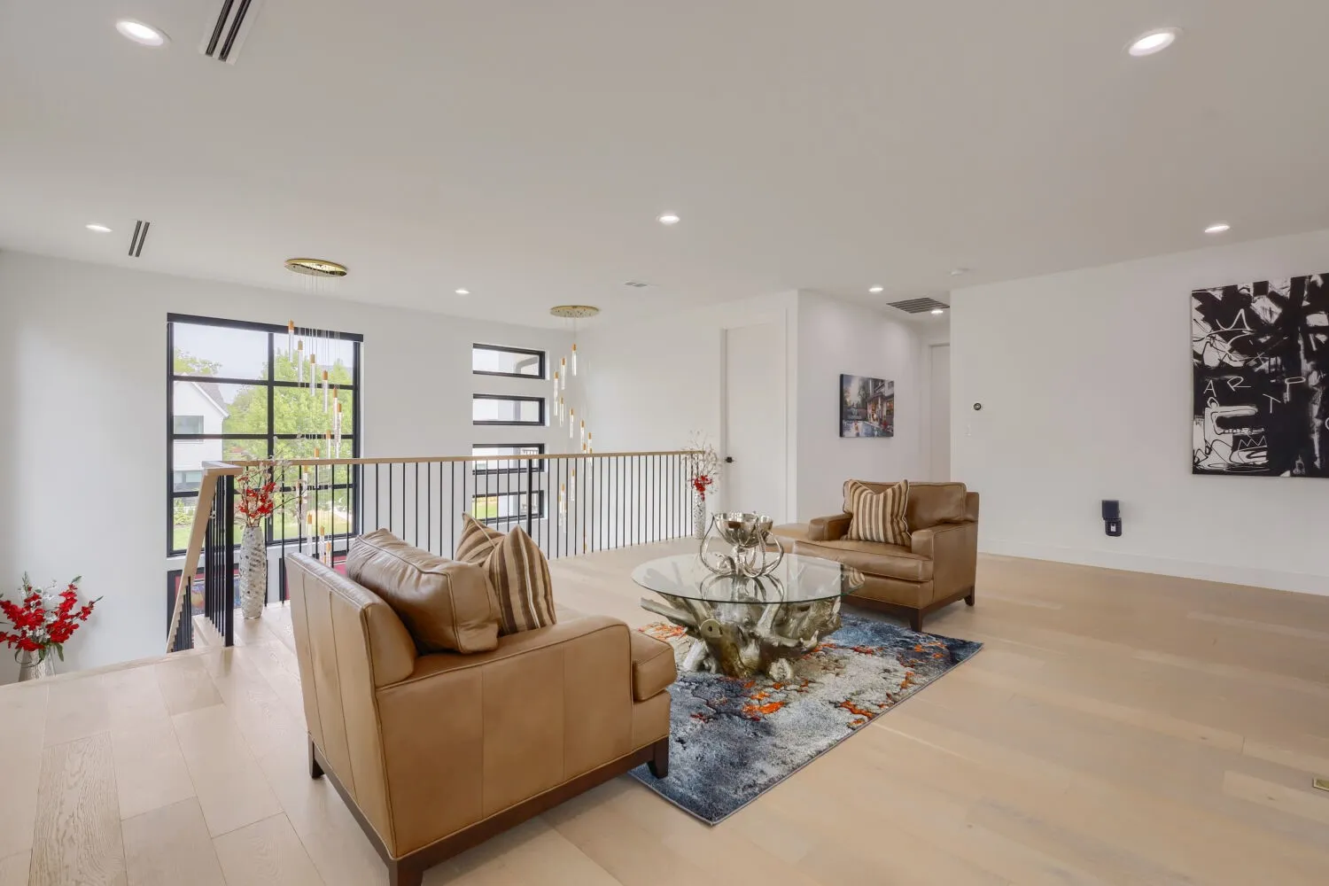Flex area Recessed lighting, light wood-finish flooring, black-framed windows, and a black metal and wood railing