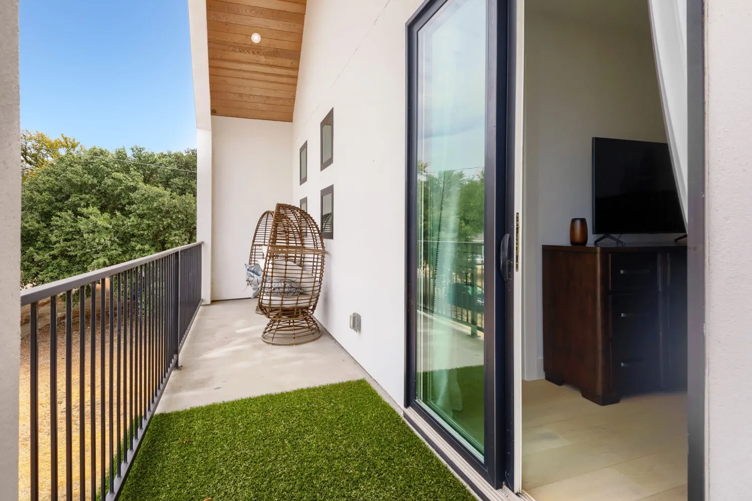 Balcony featuring a black metal railing, concrete flooring, and a wood-finish ceiling