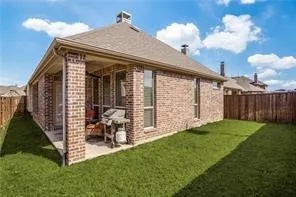 Brick exterior with a covered patio, concrete slab, and wood privacy fence