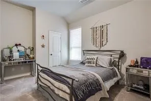 Vaulted ceiling, neutral wall paint, carpeted flooring, window with blinds, and a white interior door