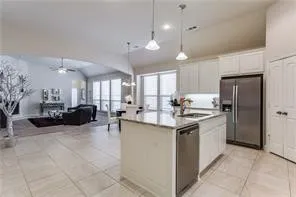 Kitchen with stainless steel appliances, a center island with a sink, white cabinetry, and pendant lighting