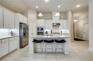 Kitchen featuring white cabinetry, a central island with countertop seating, stainless steel appliances, and recessed lighting