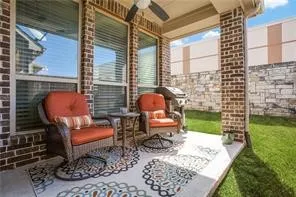 Covered patio featuring a ceiling fan, brick exterior, and stone veneer wall