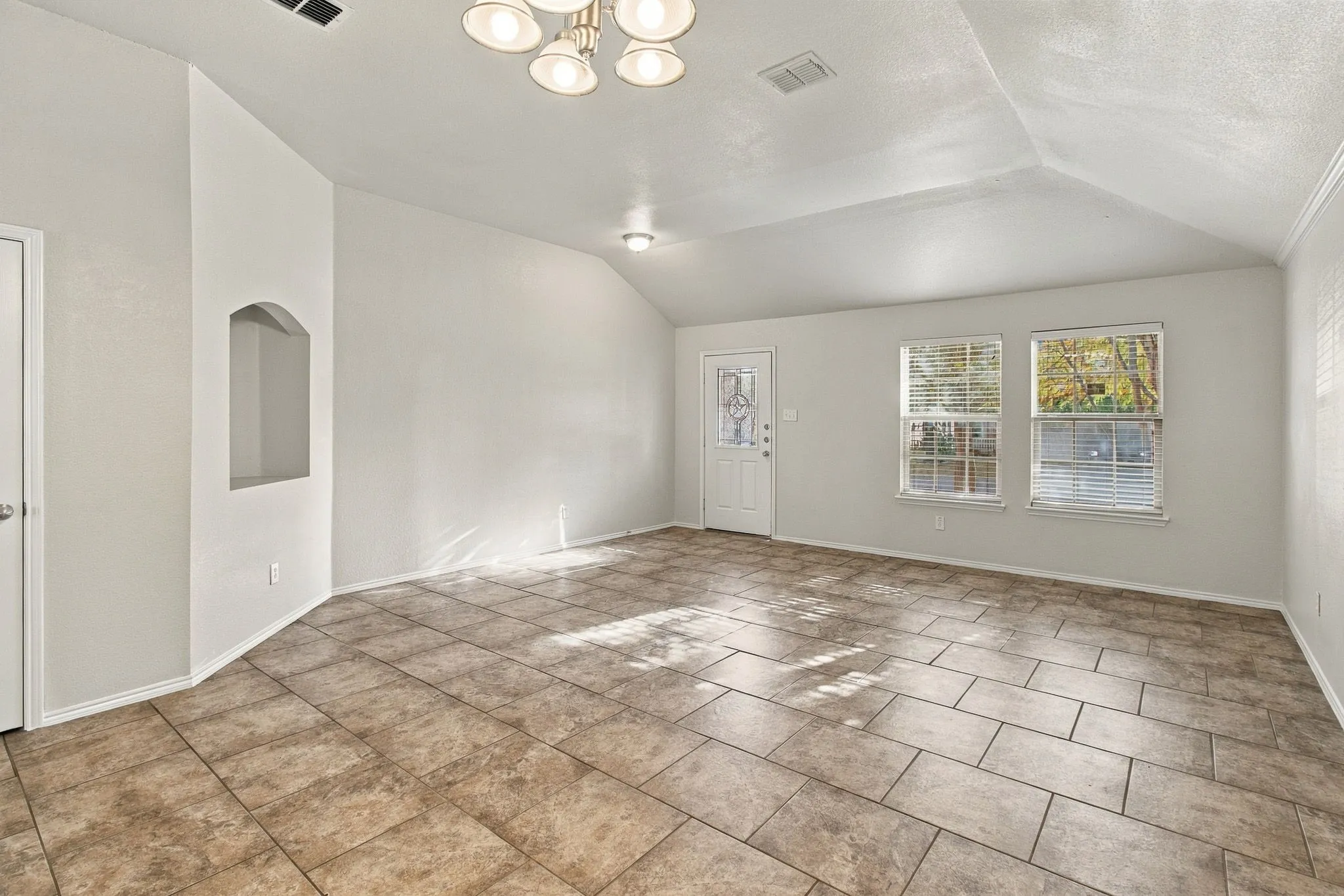 Vaulted ceilings, recessed lighting, and a decorative arched niche complement the tile flooring and multiple windows
