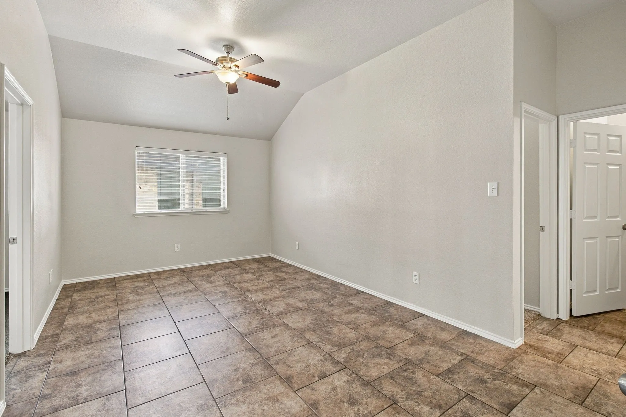 Vaulted ceiling, tiled flooring, ceiling fan with integrated lighting, window with blinds, and white interior doors