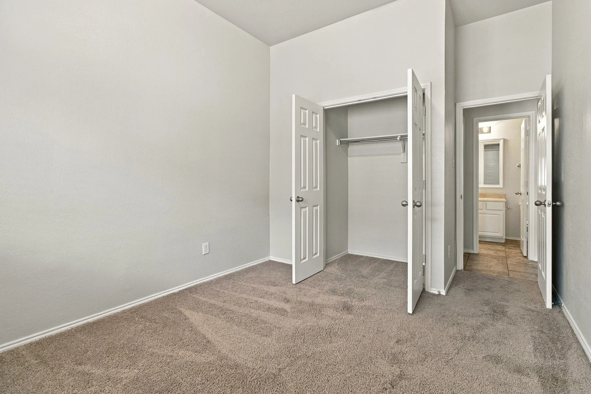 Carpeted flooring, vaulted ceiling, white interior doors, built-in closet, and a neutral wall color