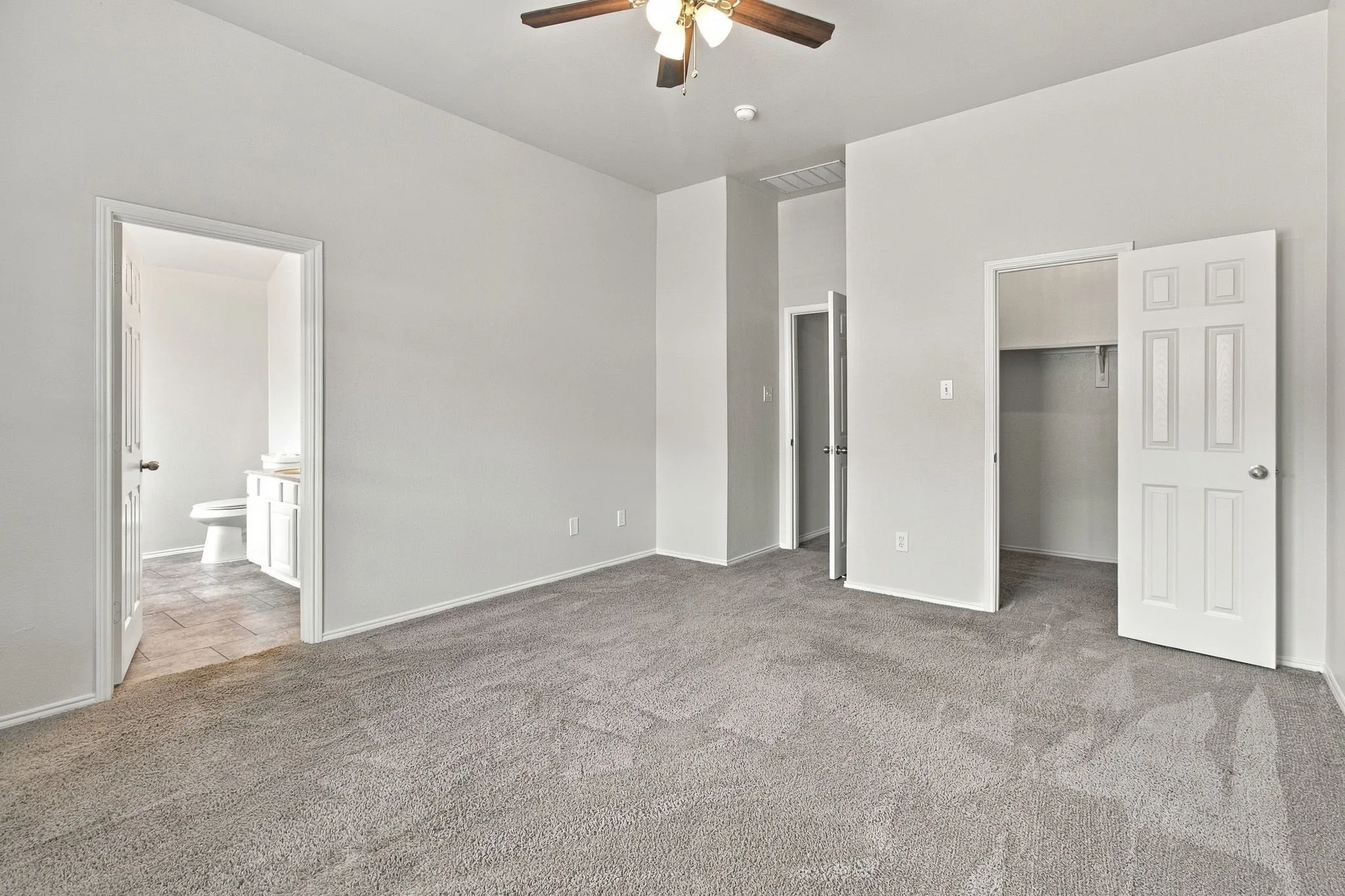 Carpeted room featuring a ceiling fan, a white paneled door, and a built-in closet