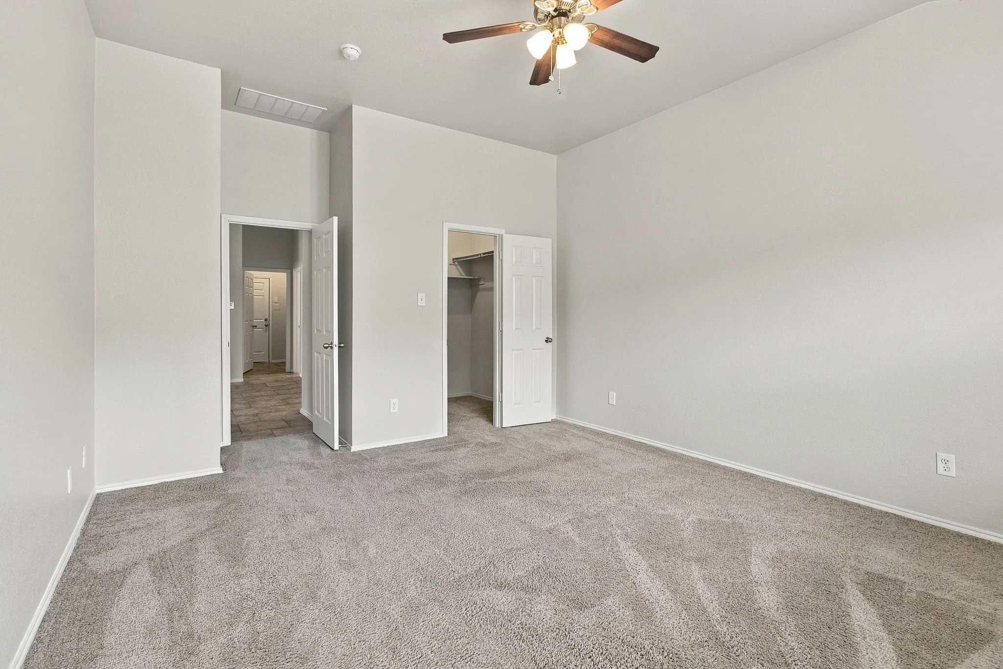 Carpeted room featuring a ceiling fan, a closet with shelving, and a doorway opening to a hallway