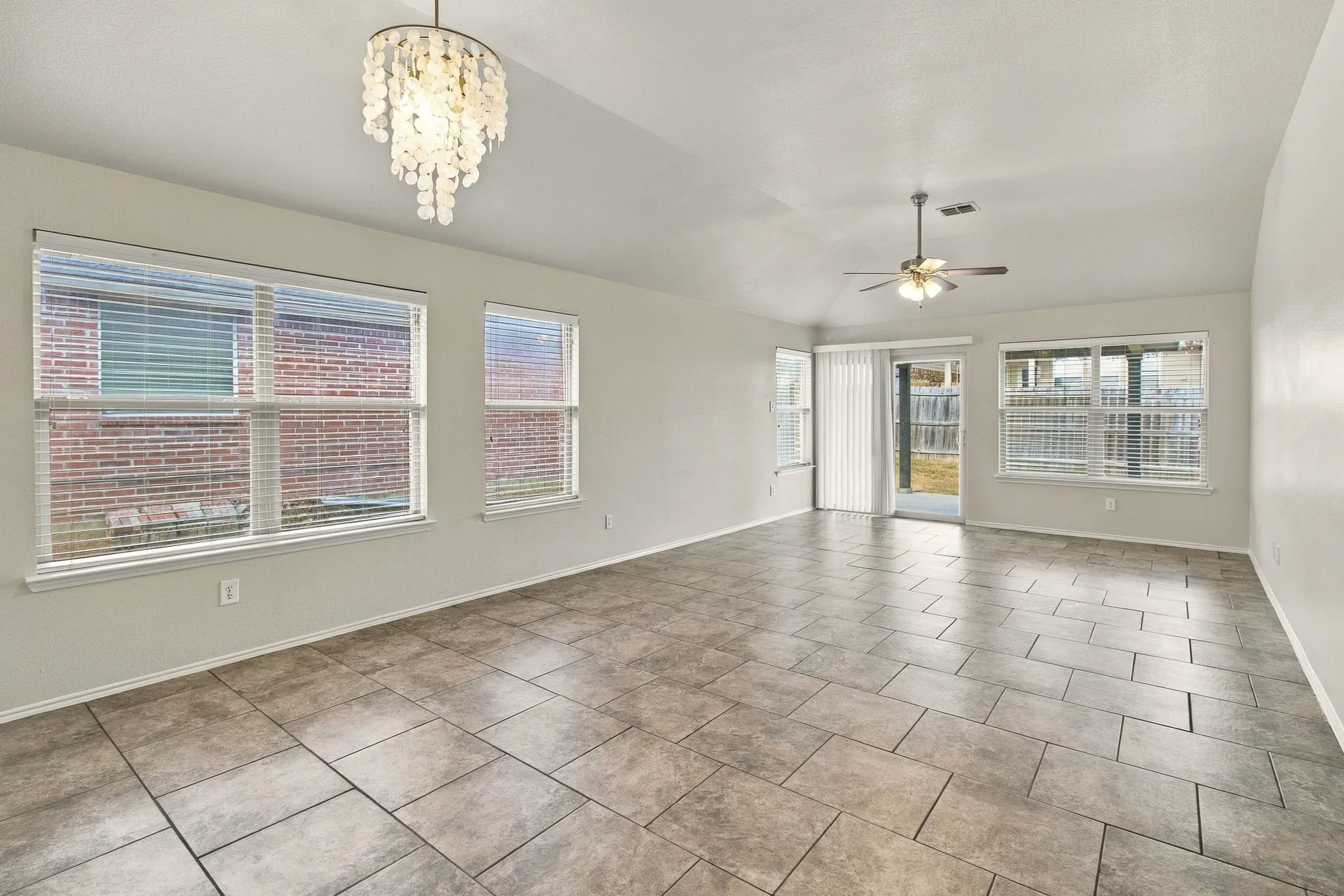 Ceramic tile flooring, multiple windows with blinds, sliding glass door, and a ceiling fan with integrated lighting
