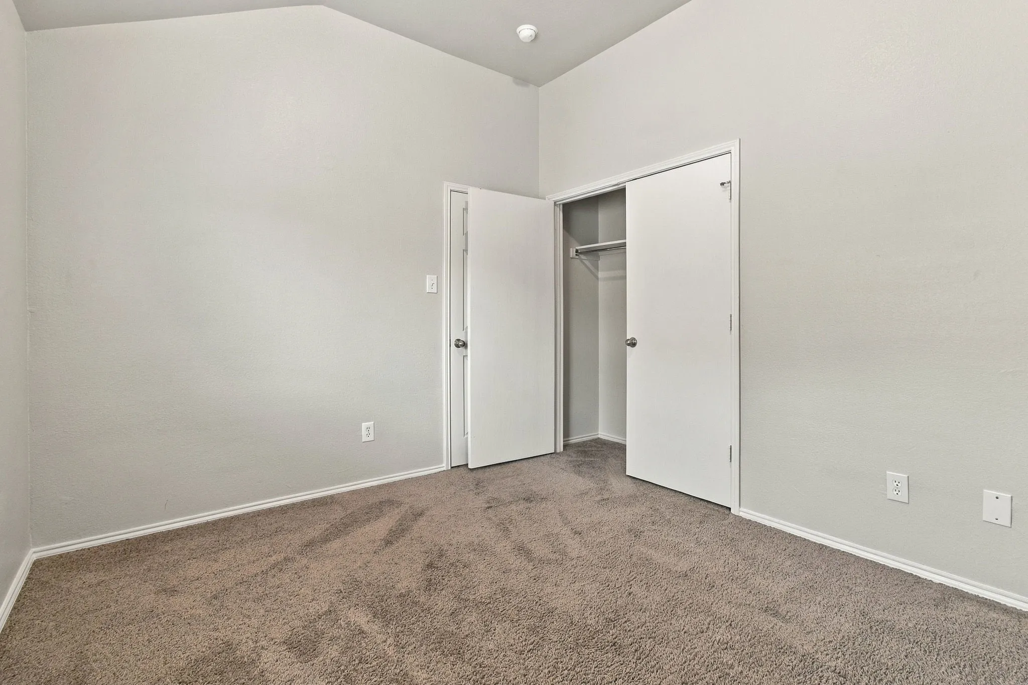Neutral-toned wall paint, carpeted flooring, and a built-in closet with shelving