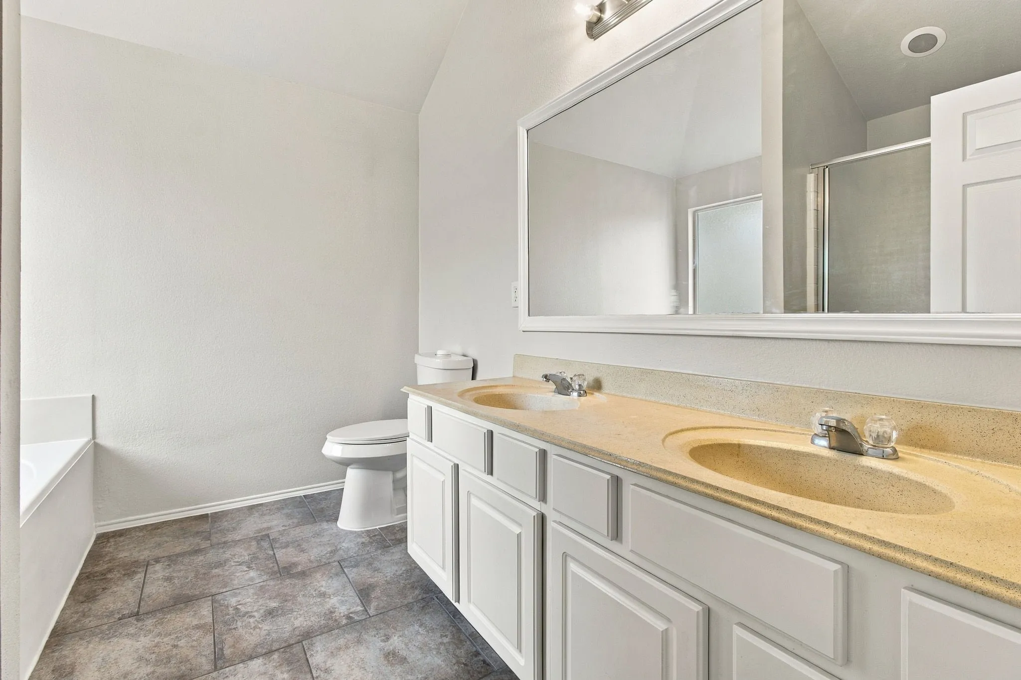 Dual vanity with integrated sinks, white cabinetry, a large mirror, and tiled flooring