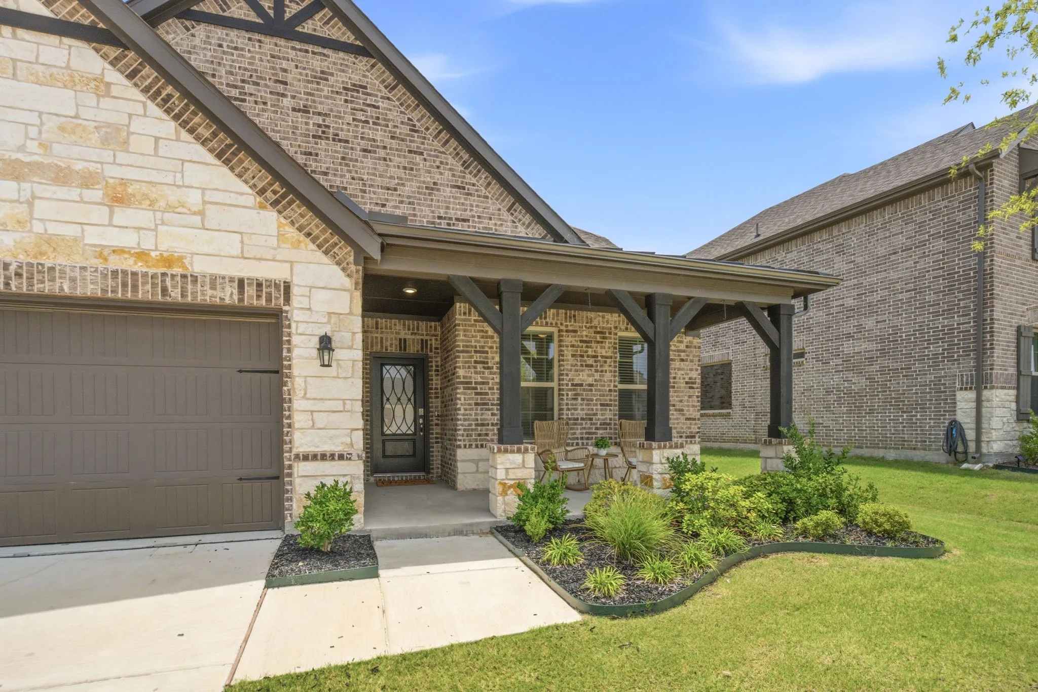 Beautiful curb appeal at 905 Bluebell St in Princeton, TX with stone-and-brick elevation, covered front porch, and rare 3-car garage.