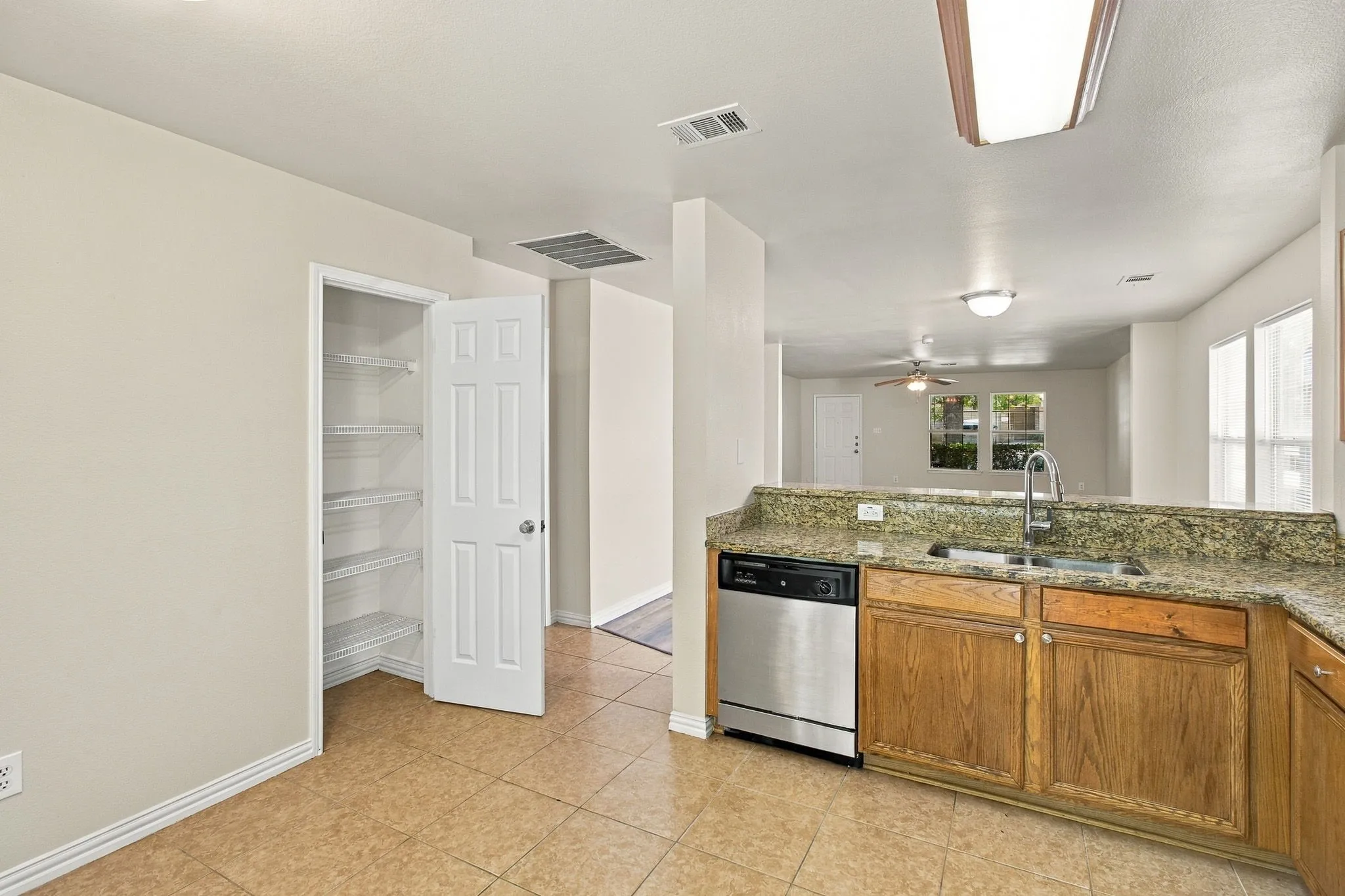 Kitchen featuring a stainless steel dishwasher, double basin sink with a high-arc faucet, wood cabinetry, and a stone countertop