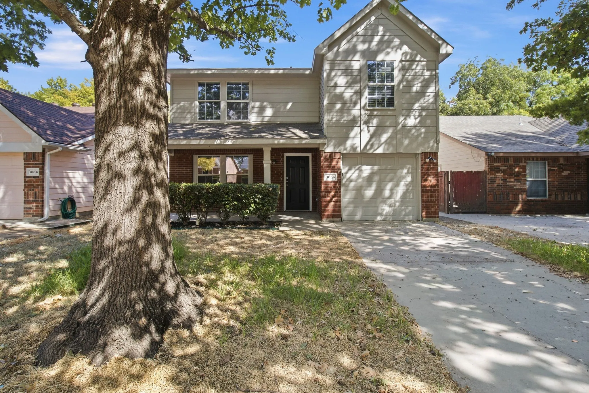 Two-story facade with brick and siding, covered entry, and attached garage