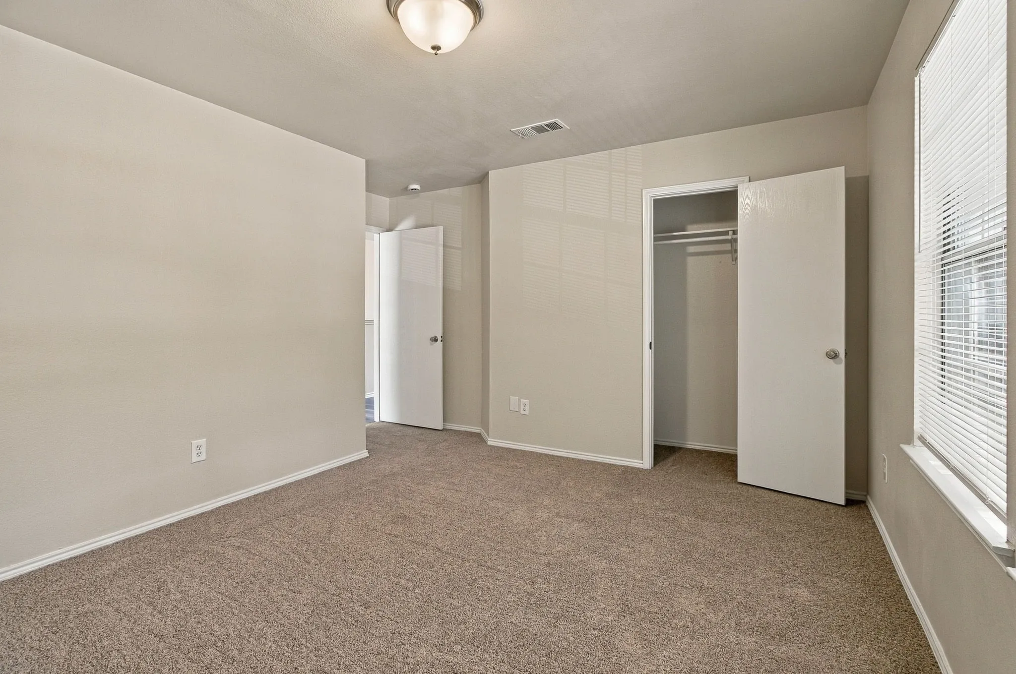 Neutral tone wall paint, textured carpet flooring, built-in closet, and a ceiling-mounted light fixture