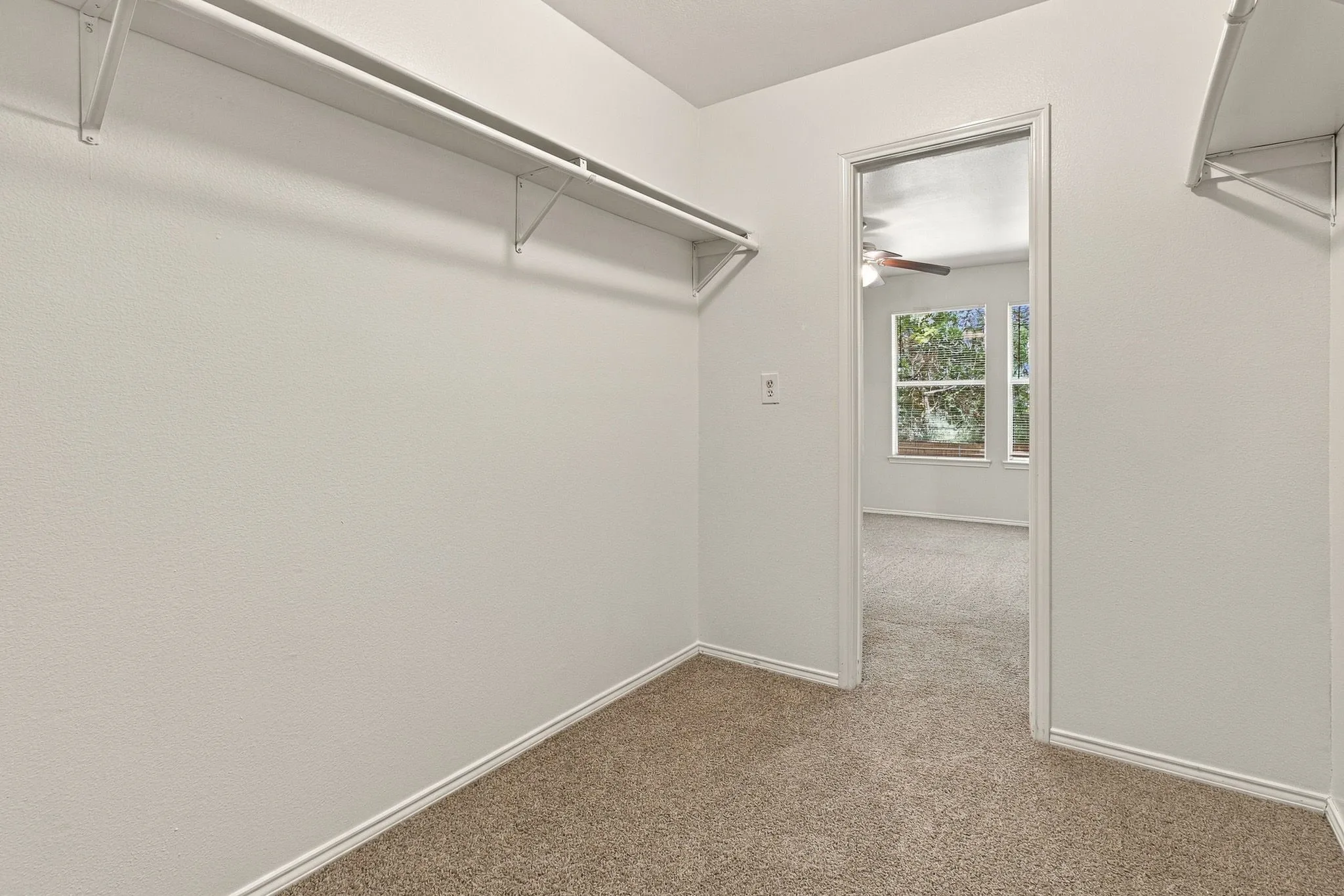 Walk-in closet with white shelving and hanging rods