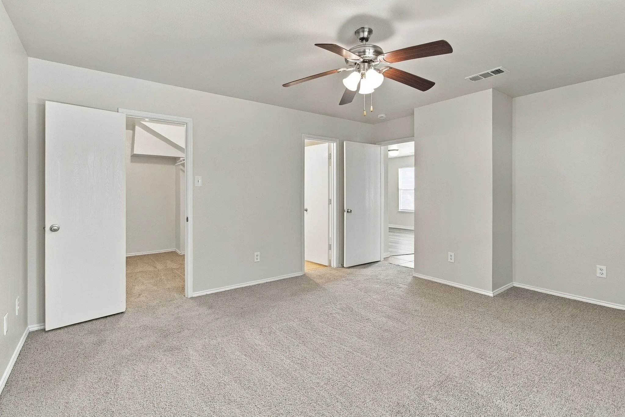 Carpeted flooring, ceiling fan with integrated lighting, multiple doorways, and neutral wall tones