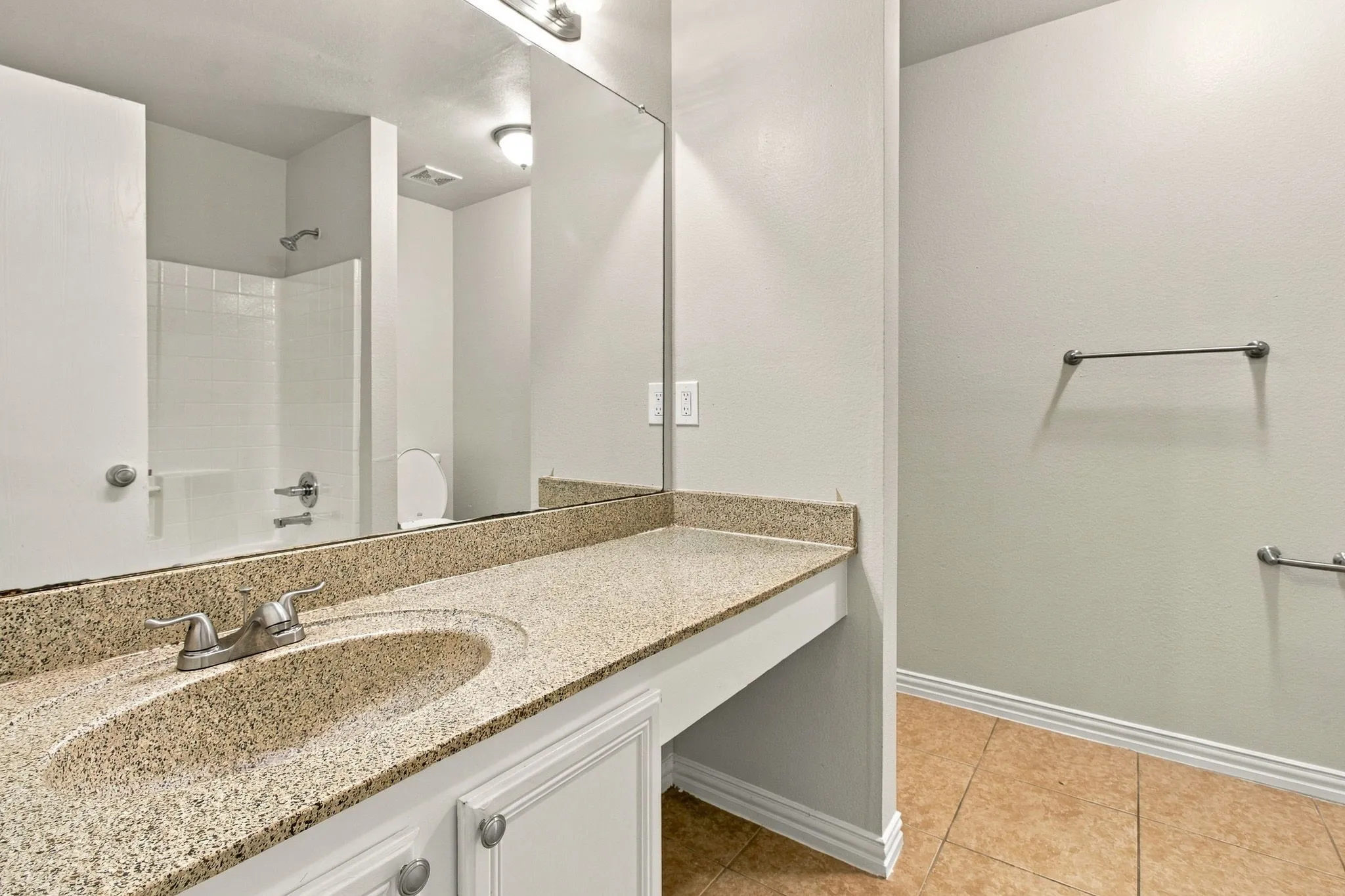Vanity with a speckled countertop, integrated sink, and brushed nickel faucet