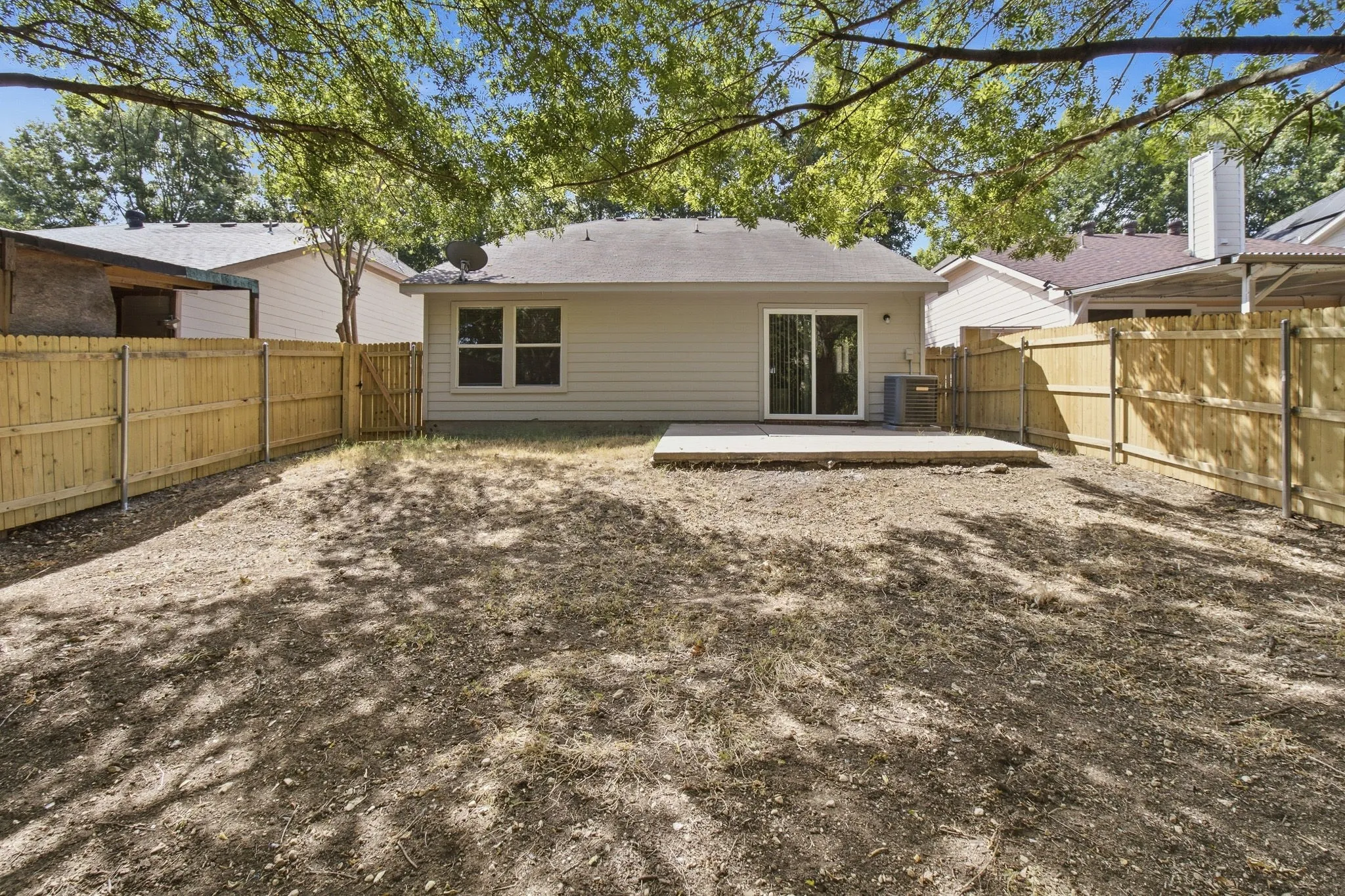 Private backyard with wood fencing, a concrete patio, and mature trees providing shade