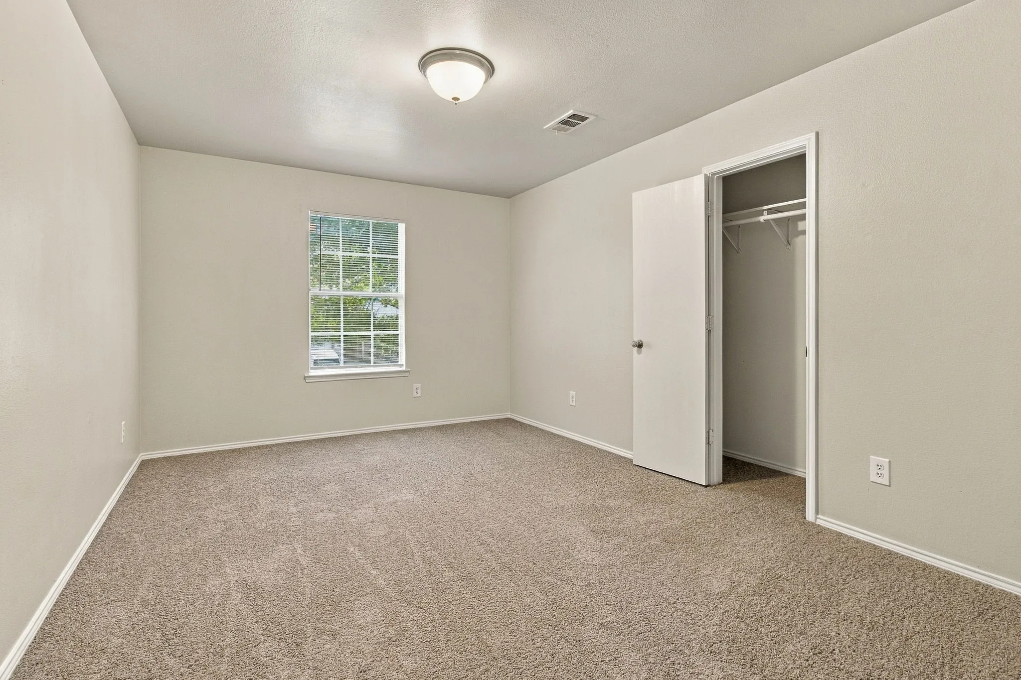 Neutral color palette, carpeted flooring, single window, flush mount lighting, and a built-in closet with shelving