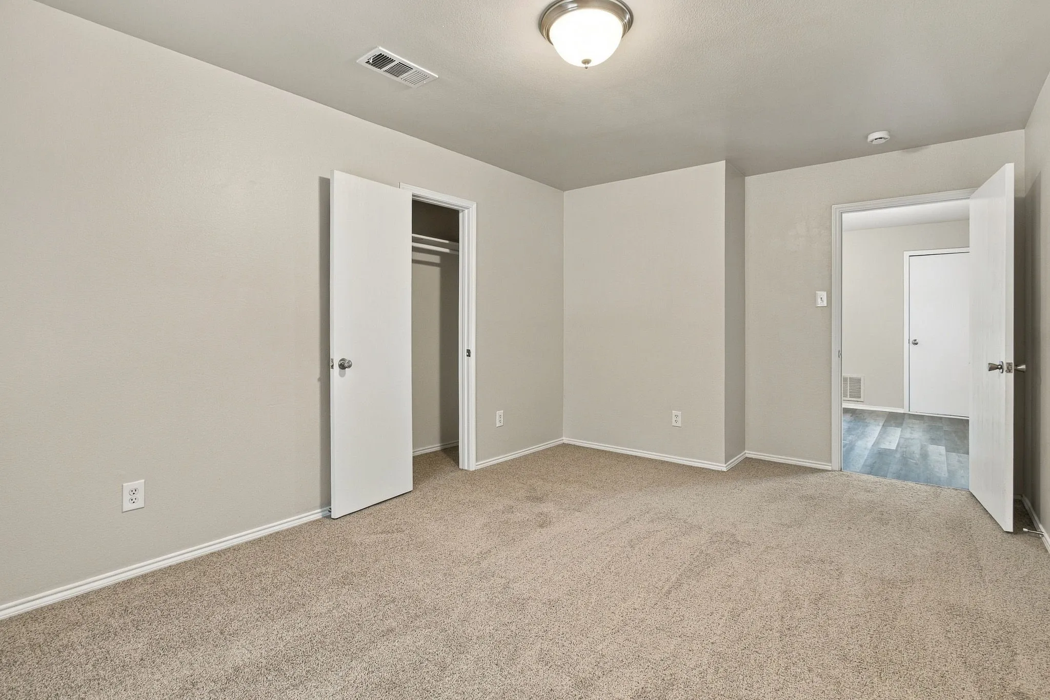 Neutral-toned carpeted flooring, light grey painted walls, and a ceiling-mounted light fixture
