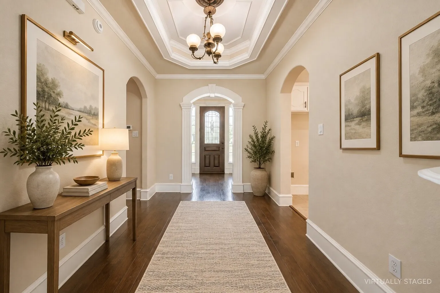 Tray ceiling with chandelier, dark wood-finish flooring, arched doorways, white crown molding, and a paneled entry door with decorative glass