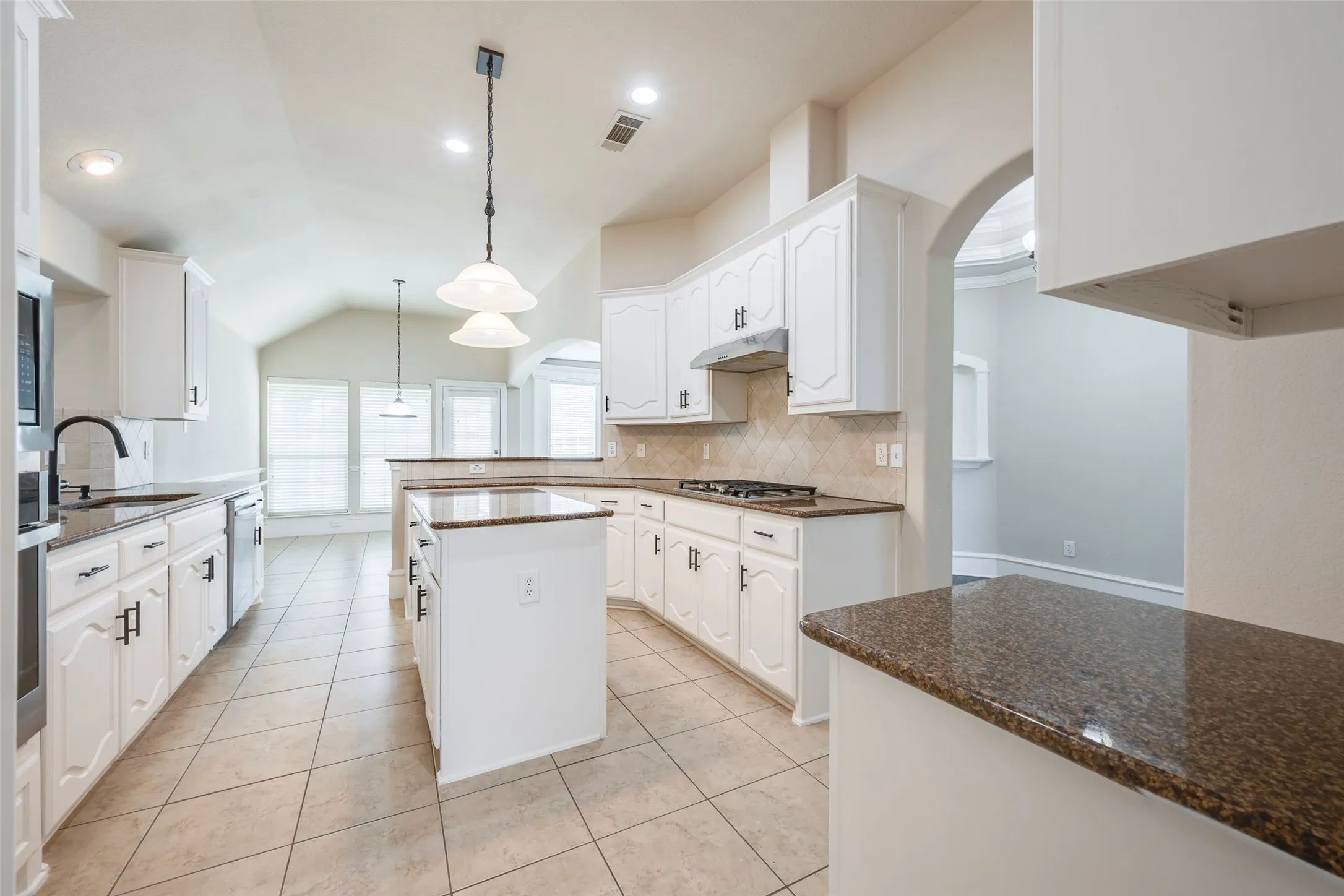 Kitchen featuring granite countertops, white cabinetry, tile flooring, a center island, and vaulted ceilings