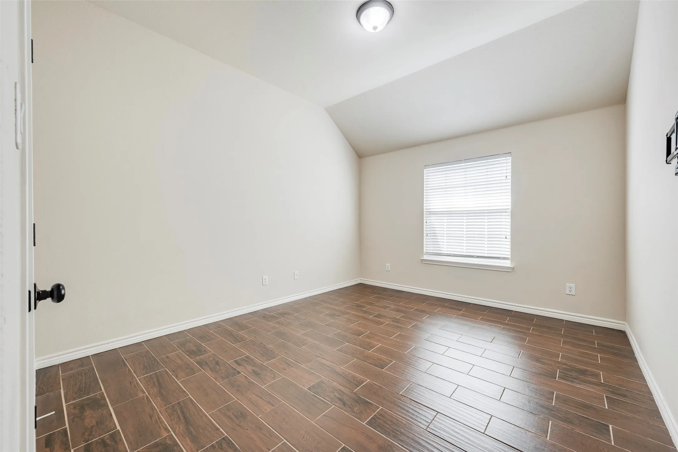 Wood-finish flooring with rectangular tile pattern, single window with blinds, and ceiling-mounted light fixture