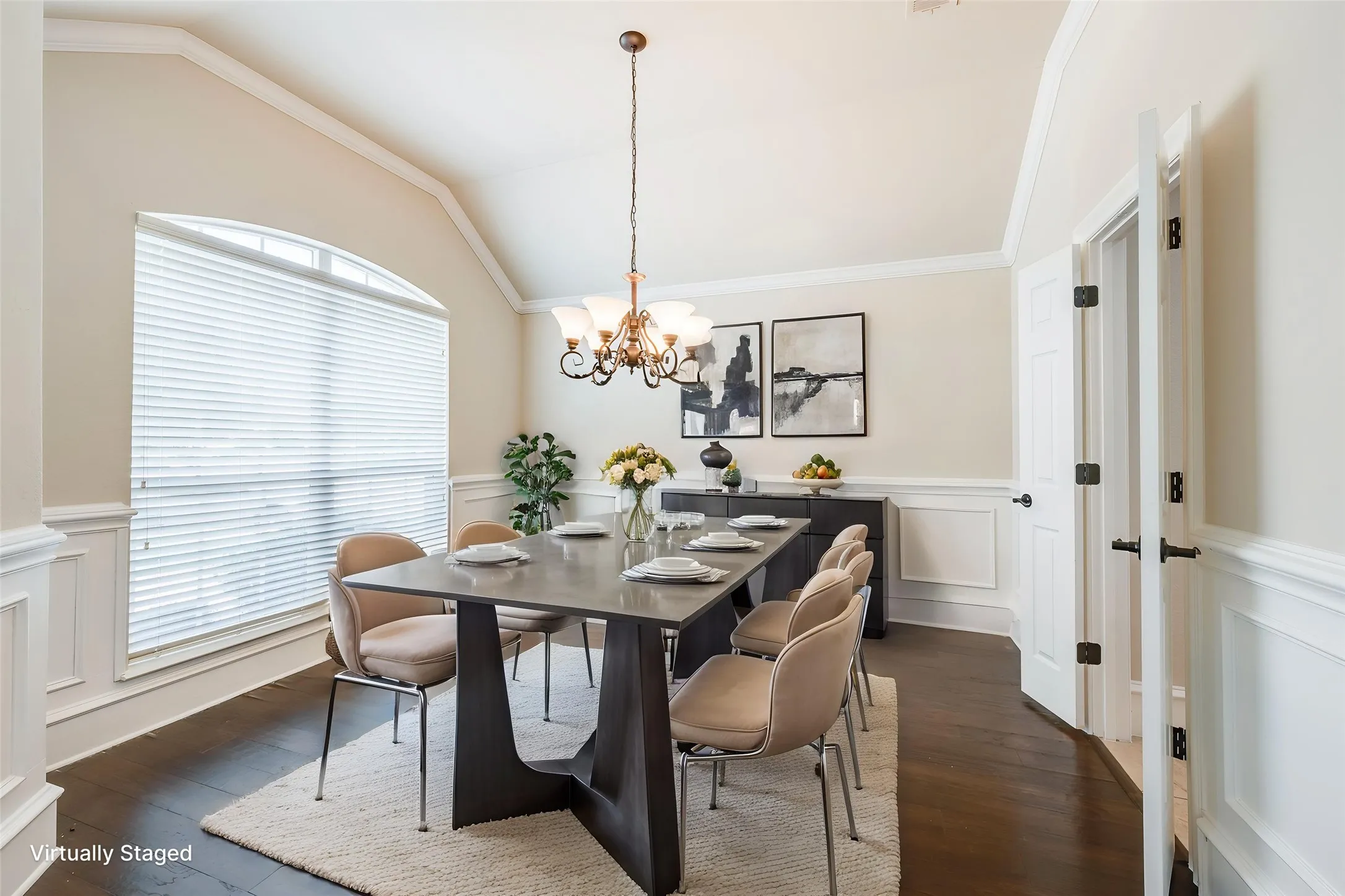 Vaulted ceiling with crown molding, wainscoting, wood-finish flooring, and an arched window