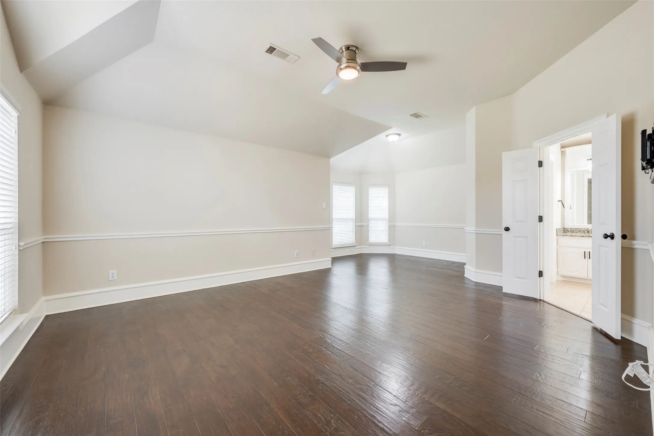 Dark wood-finish flooring, vaulted ceilings, dual windows, and crown molding