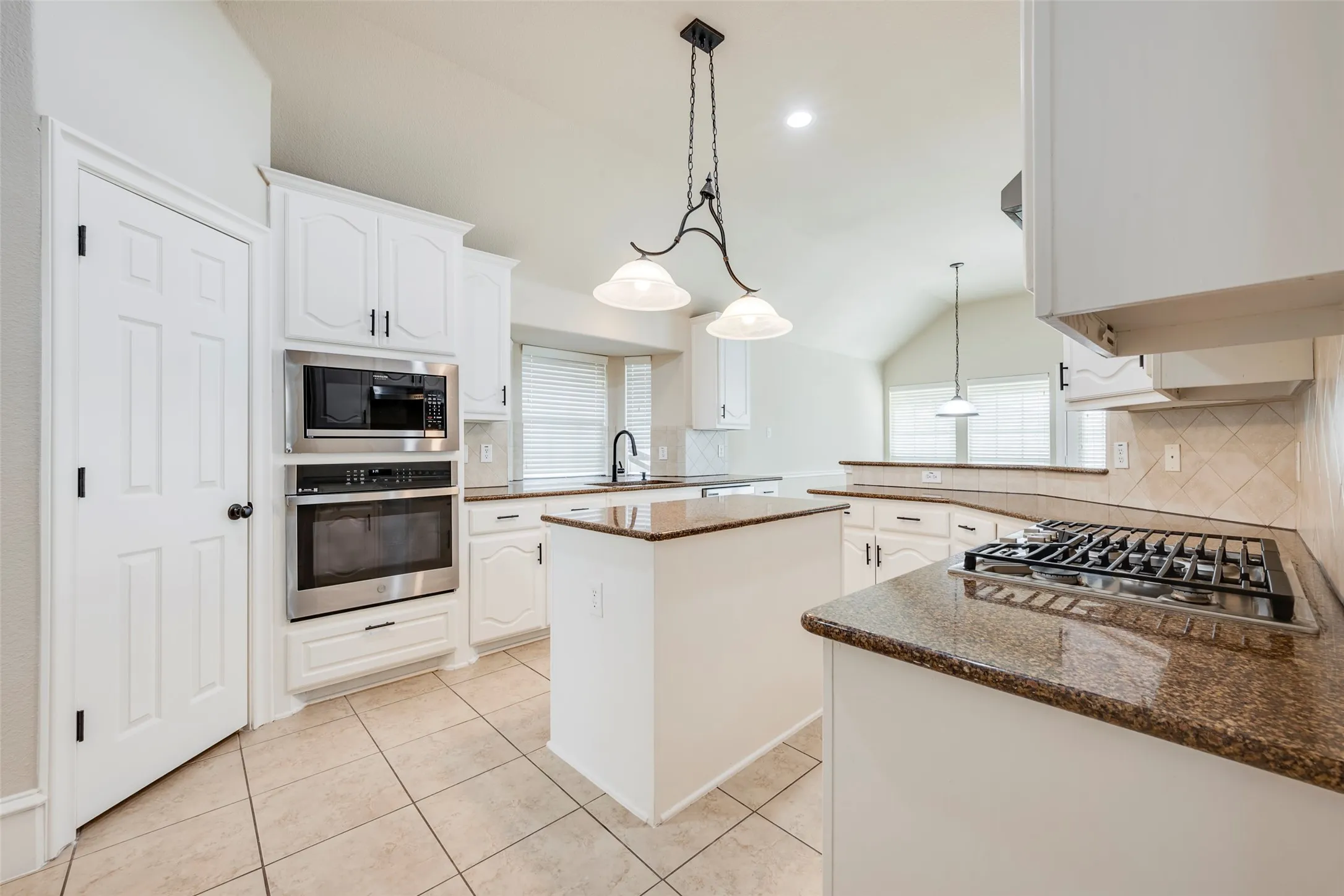 Kitchen featuring white cabinetry, granite countertops, tile flooring, and stainless steel built-in appliances