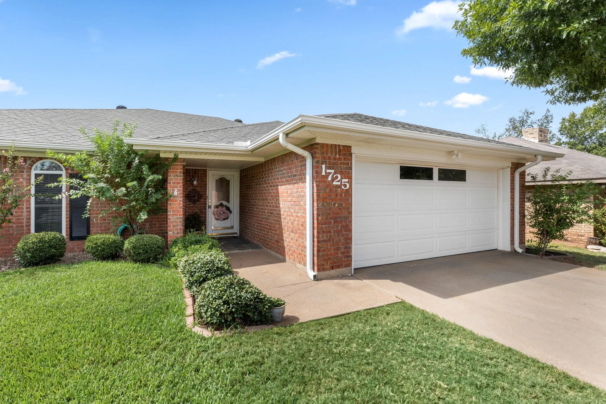 Brick exterior with white trim, an oversized garage, front porch, and an arched windows.