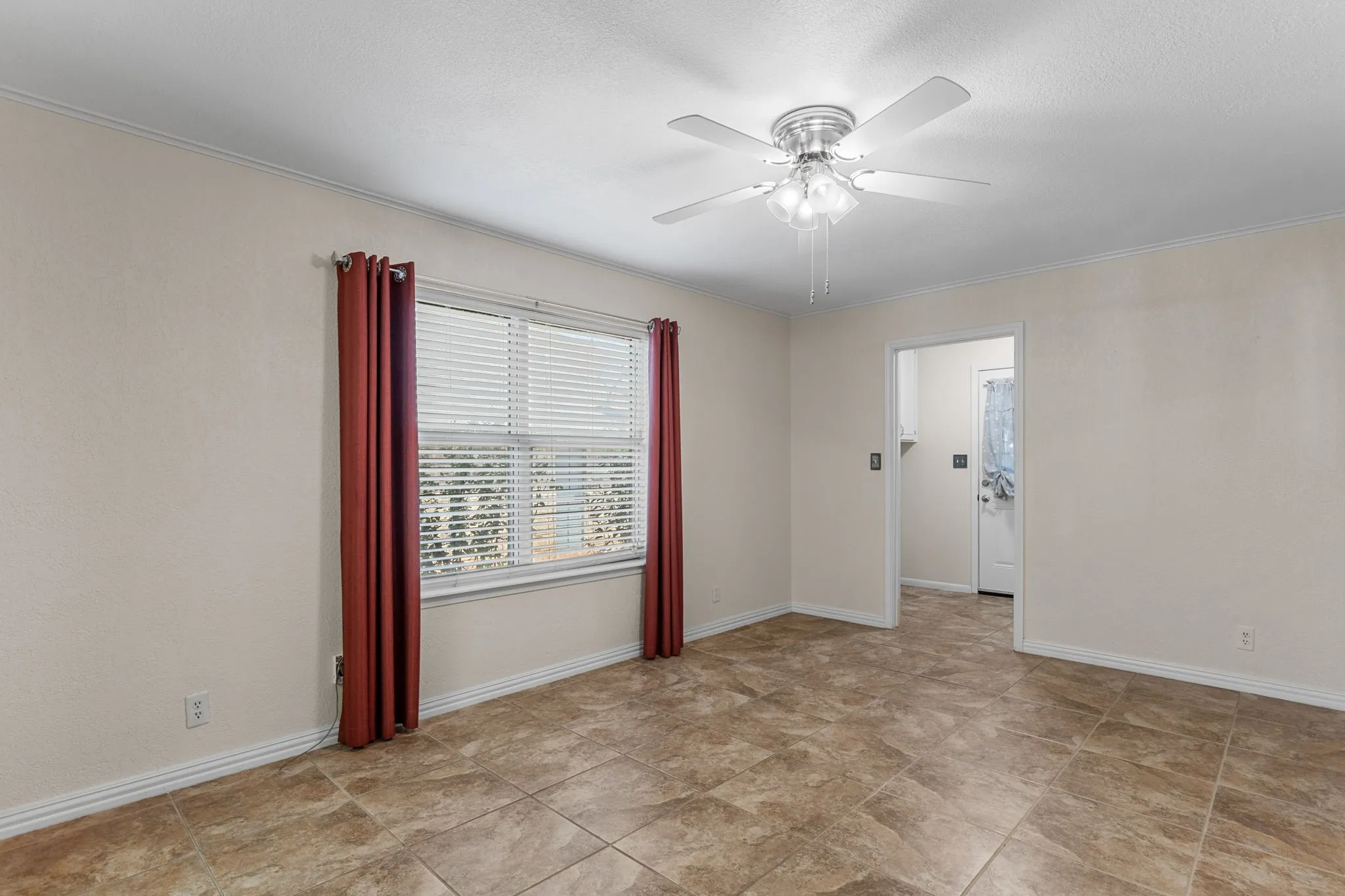 Neutral wall paint, crown molding, ceiling fan with light fixture, window with blinds, and tile flooring