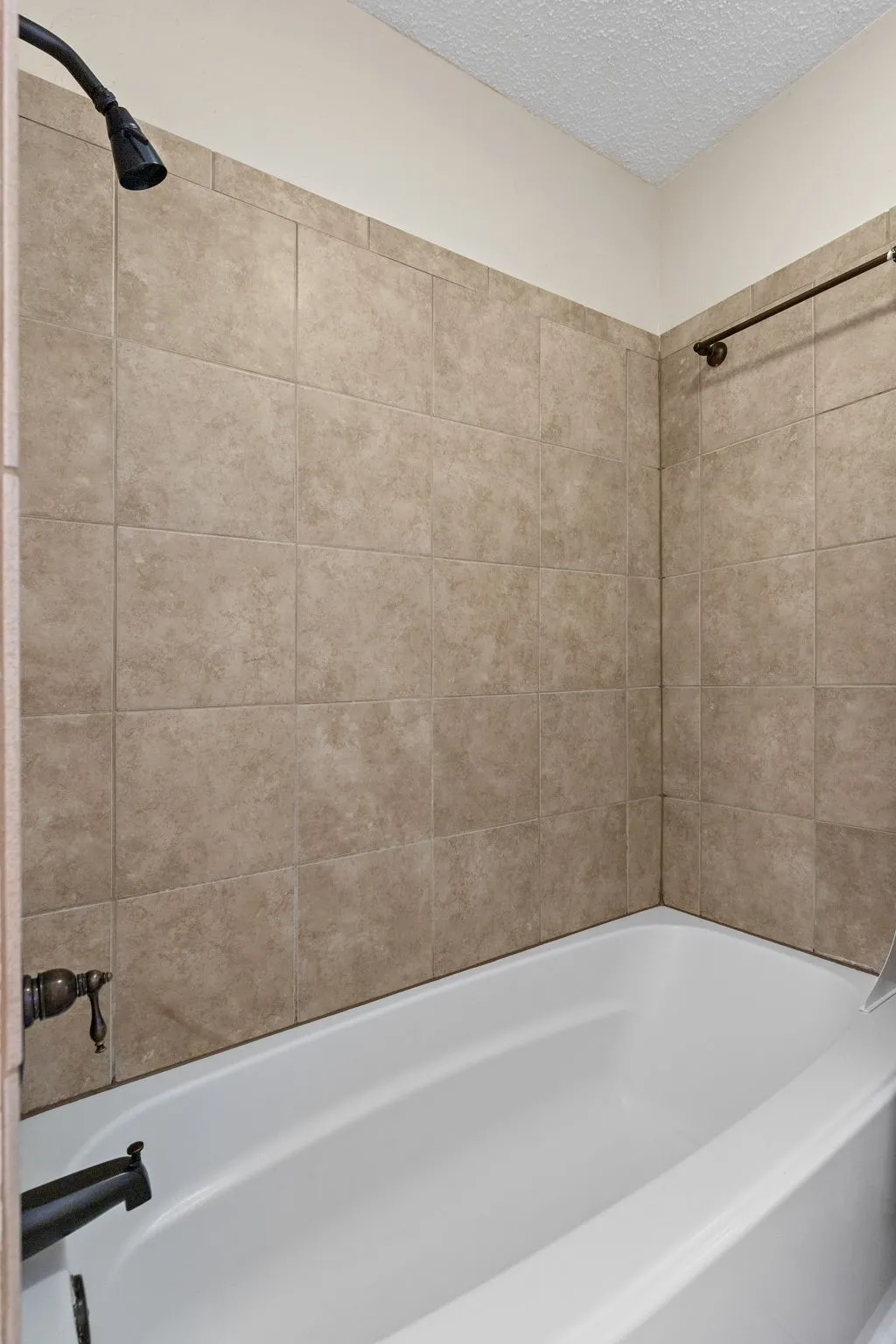 Primary bath - Bathtub with a shower fixture, tile surround, and a coordinating shower rod