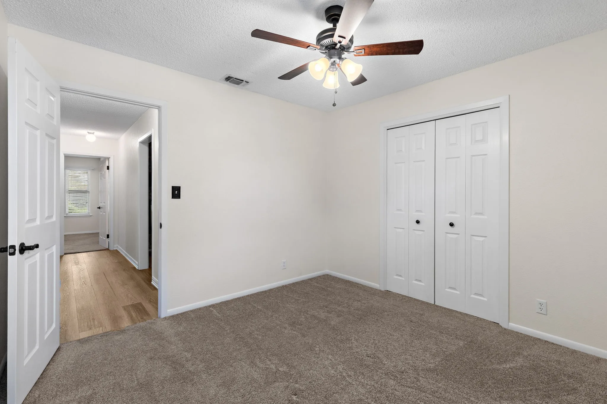 Neutral NEW wall paint, carpet flooring, a ceiling fan with light fixture, and bifold closet doors