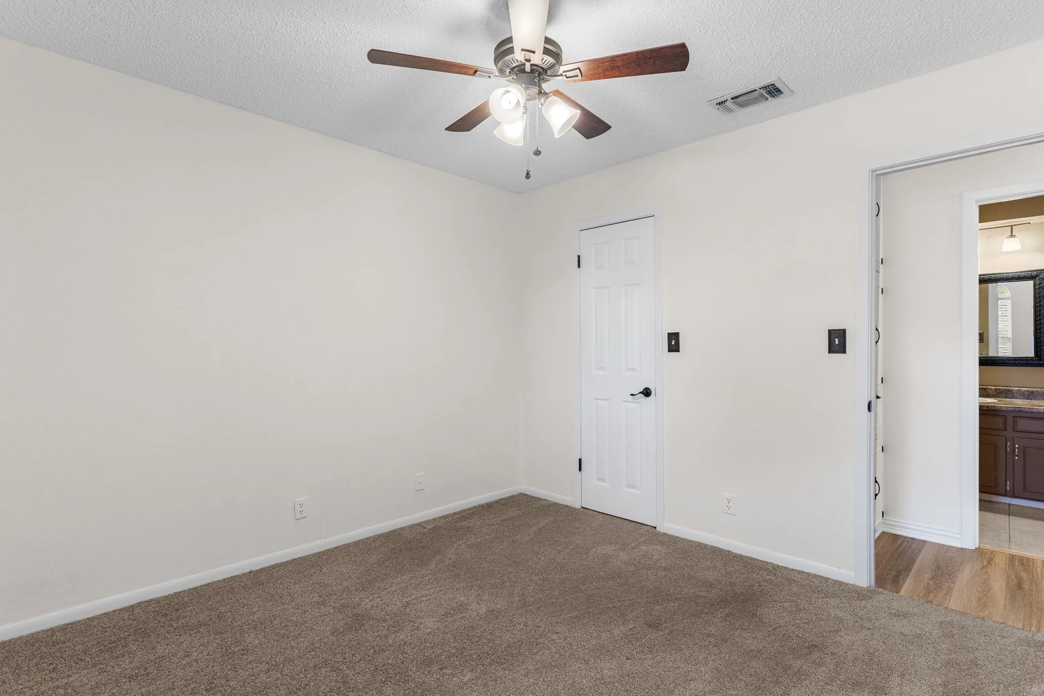 Bedroom 3 - Neutral wall color, ceiling fan with integrated lighting, carpeted flooring, and walk in closet. New paint!