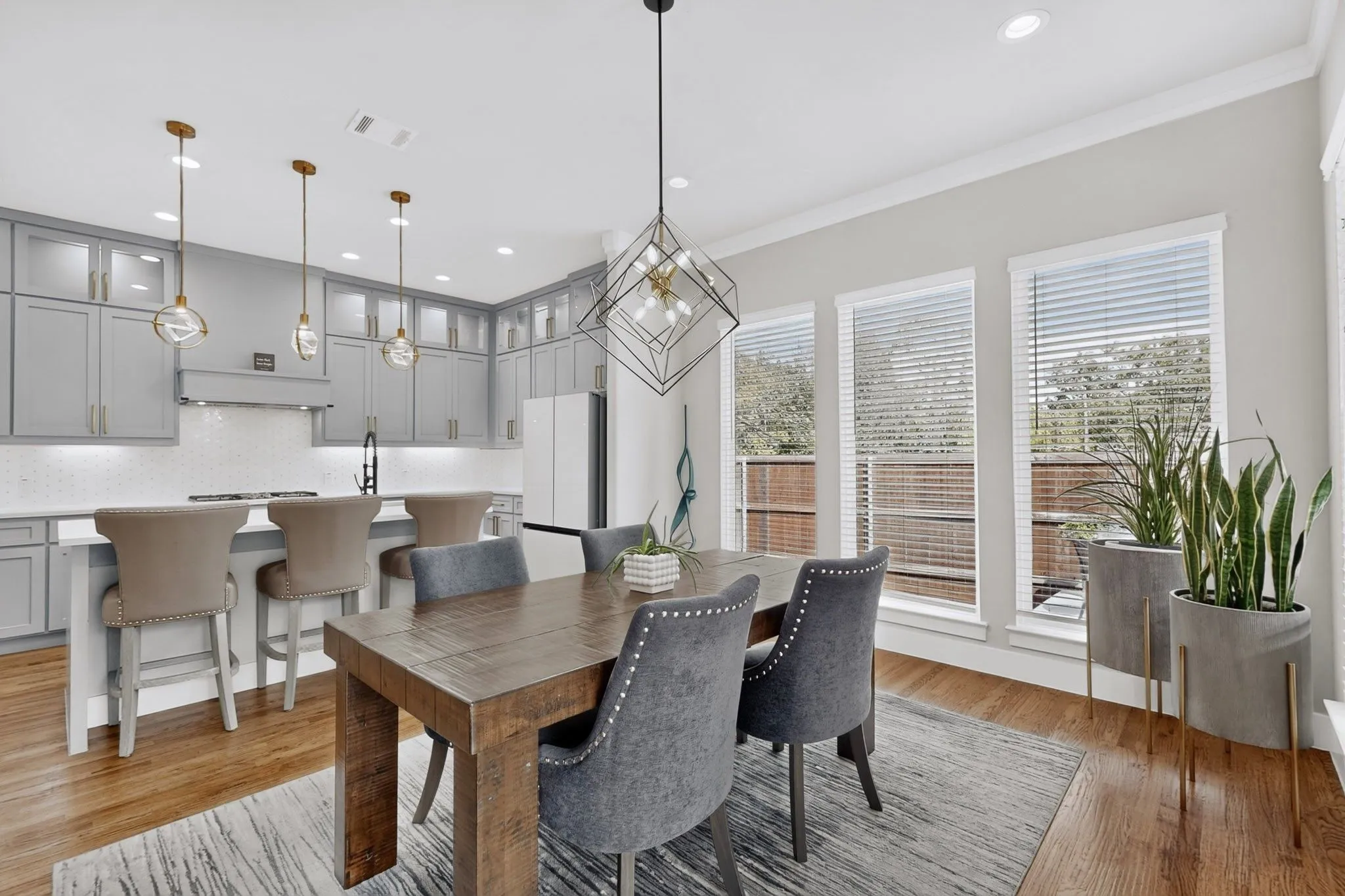 Well-appointed kitchen featuring light gray cabinetry, a white subway tile backsplash, and three pendant lights over a spacious island
