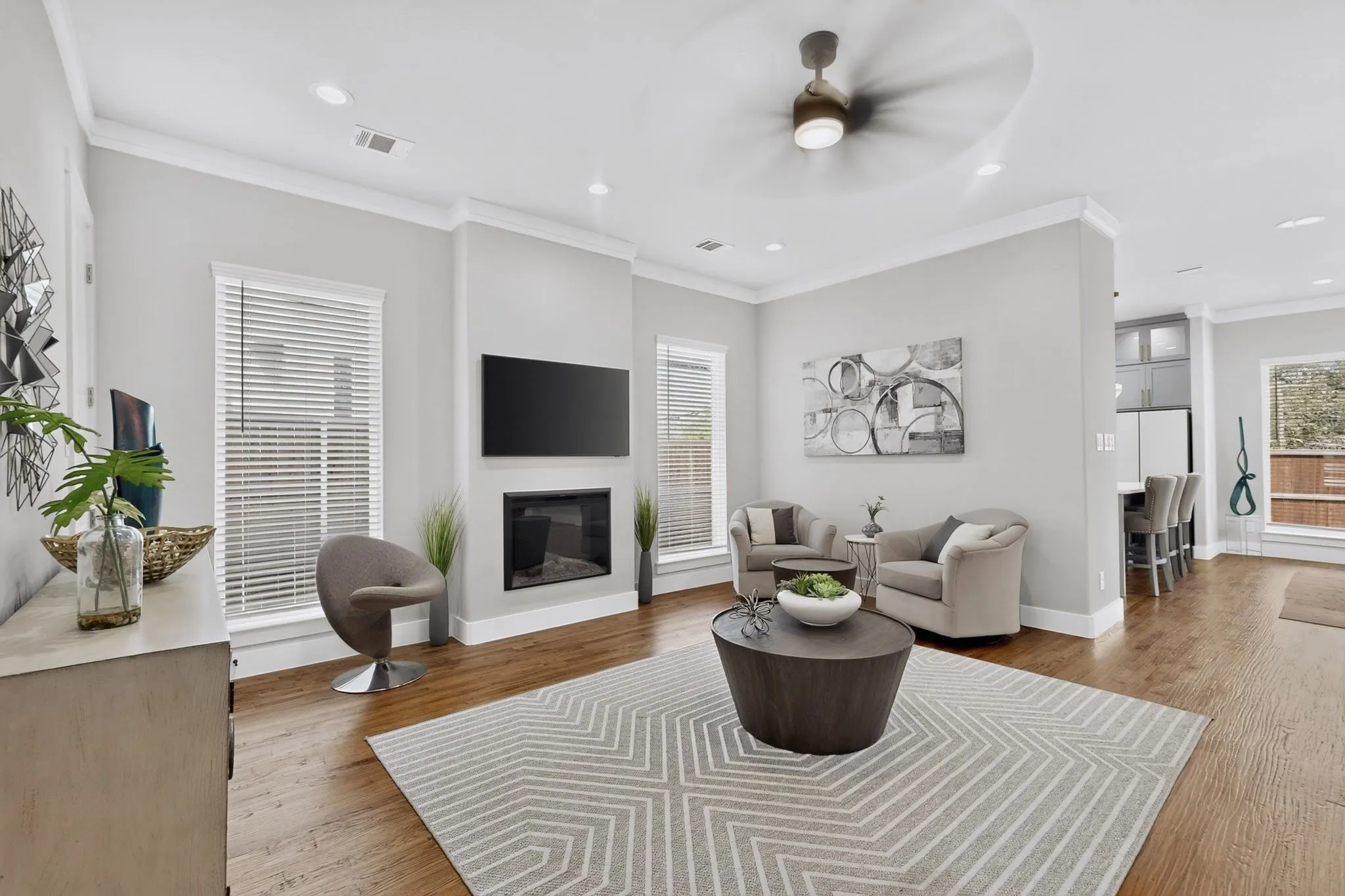 Wood-finish flooring with recessed lighting, crown molding, and a built-in fireplace