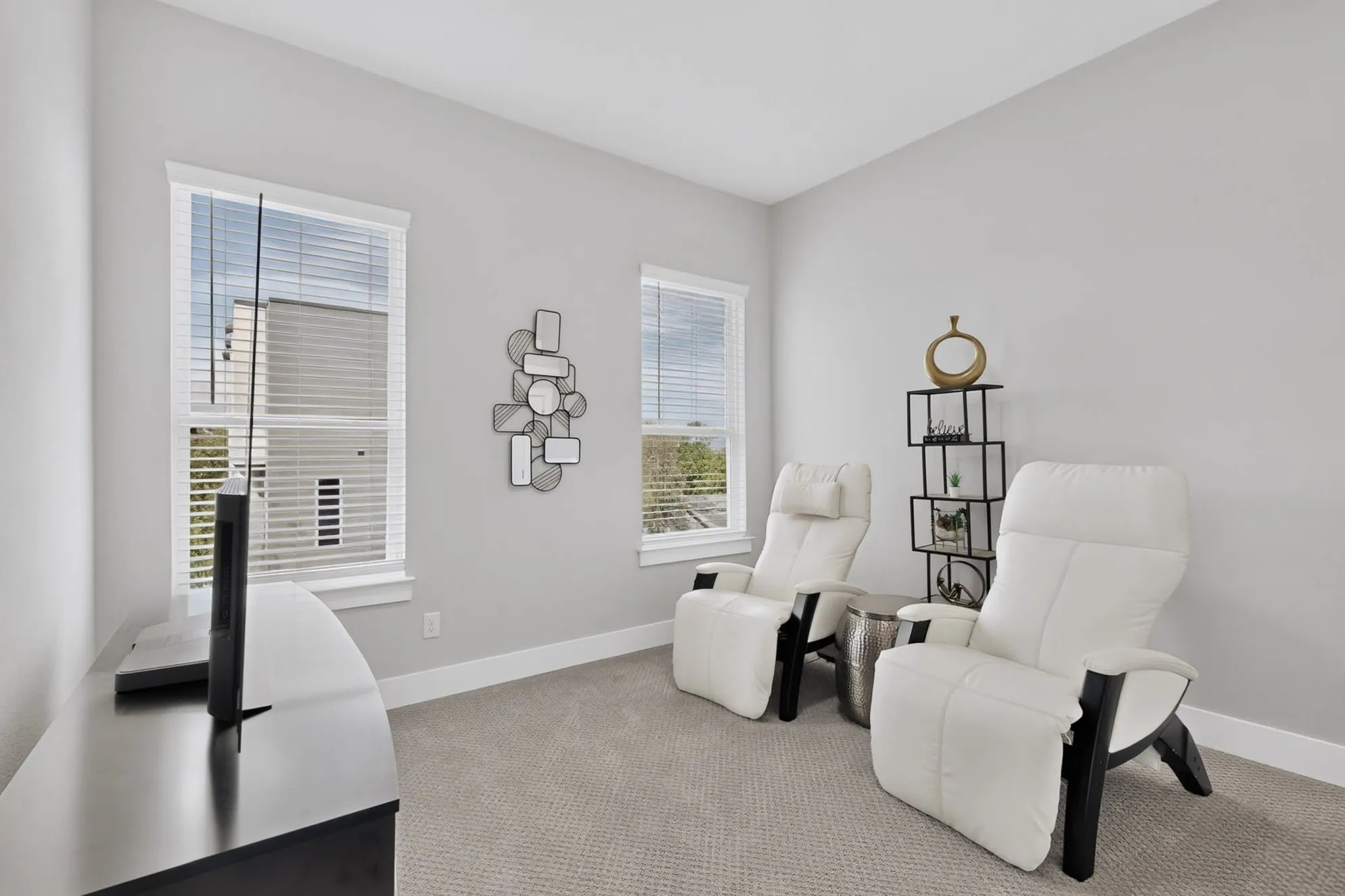 Light gray walls with white trim, two windows with blinds, and light gray carpeting