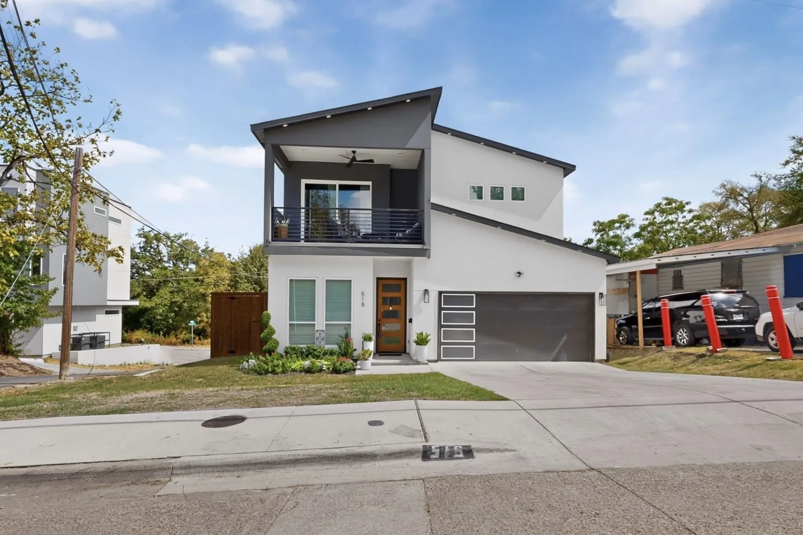 Contemporary two-story exterior with a cantilevered balcony, large sliding glass doors, and an attached two-car garage with frosted panel inserts